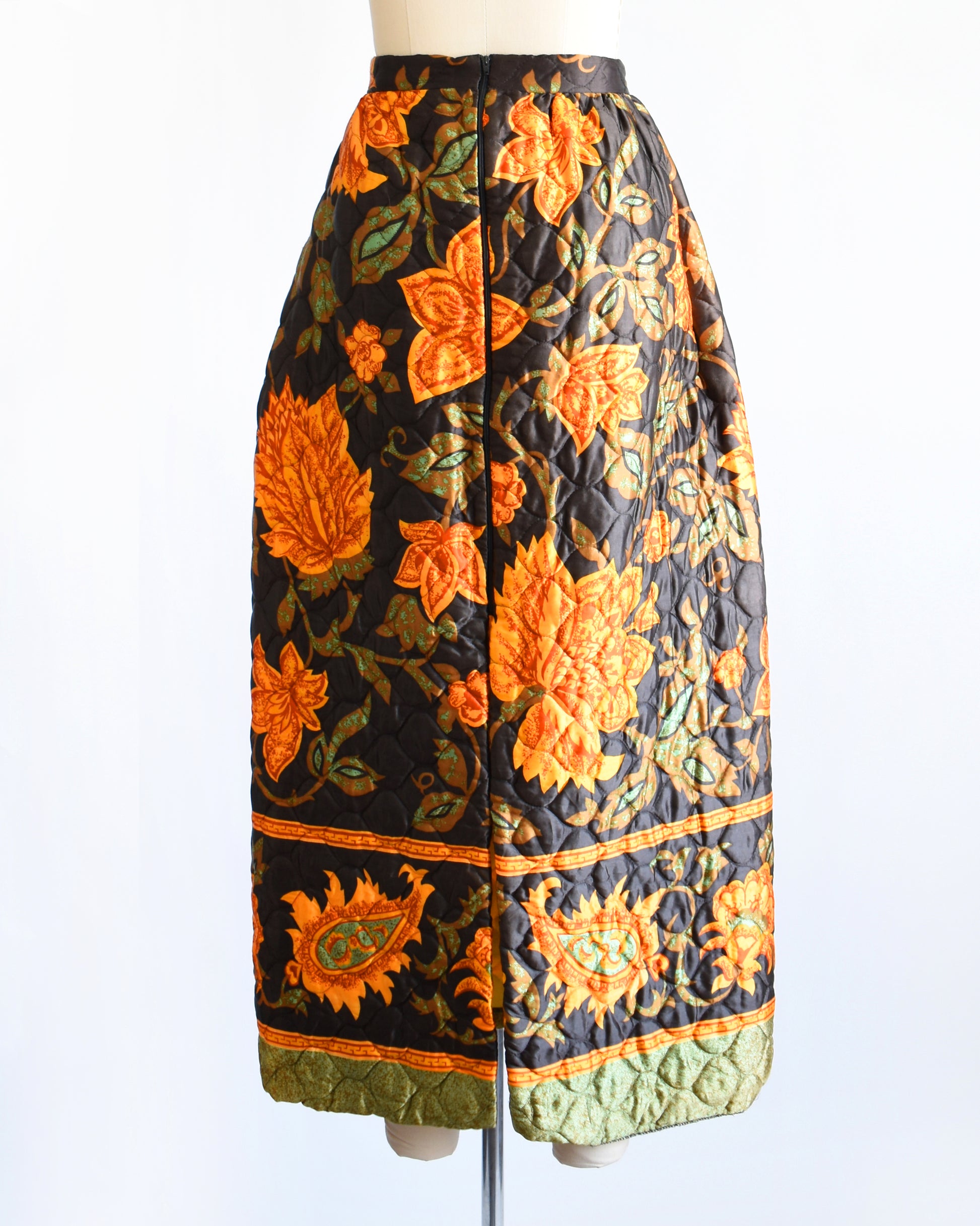back view of a vintage 1970s dark brown and orange floral patterned maxi skirt on a mannequin against a white background