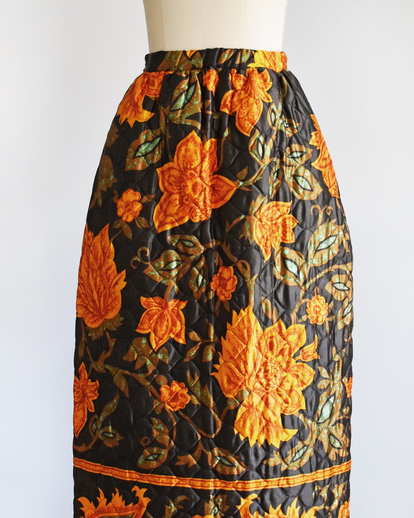 side front view of a vintage 1970s dark brown and orange floral patterned maxi skirt on a mannequin against a white background