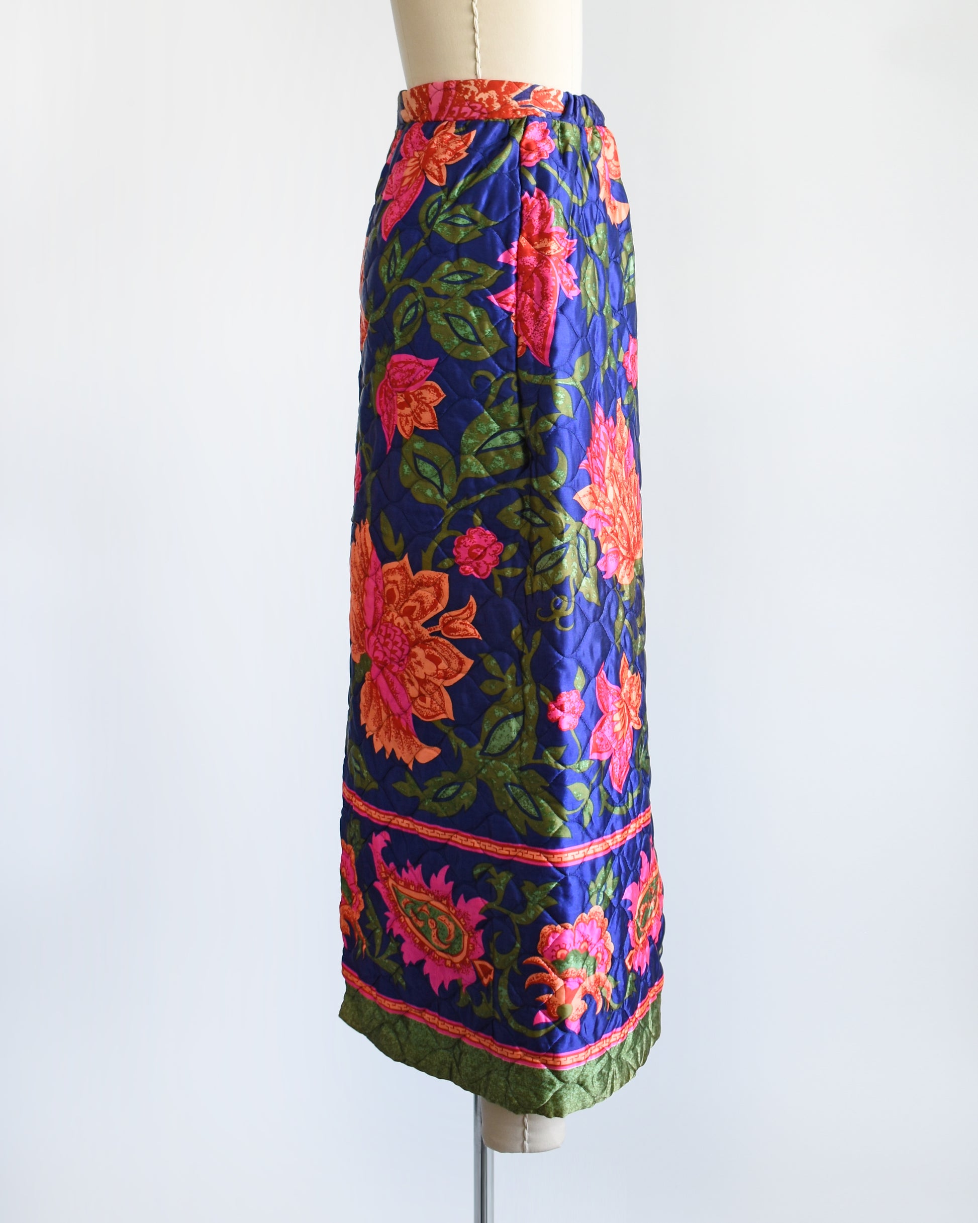 side view of a vintage 1970s blue and pink floral patterned maxi skirt on a mannequin against a white background