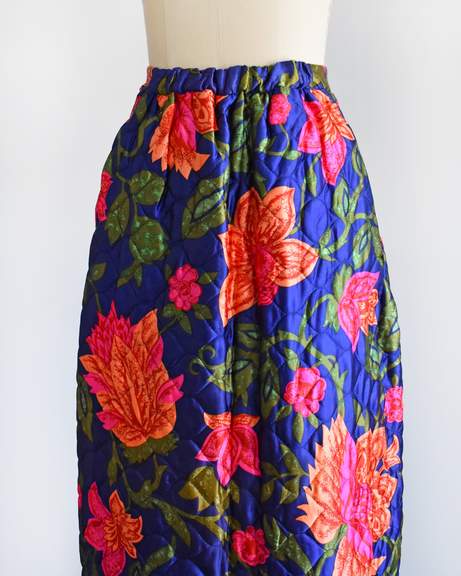 side front view of a vintage 1970s blue and pink floral patterned maxi skirt on a mannequin against a white background