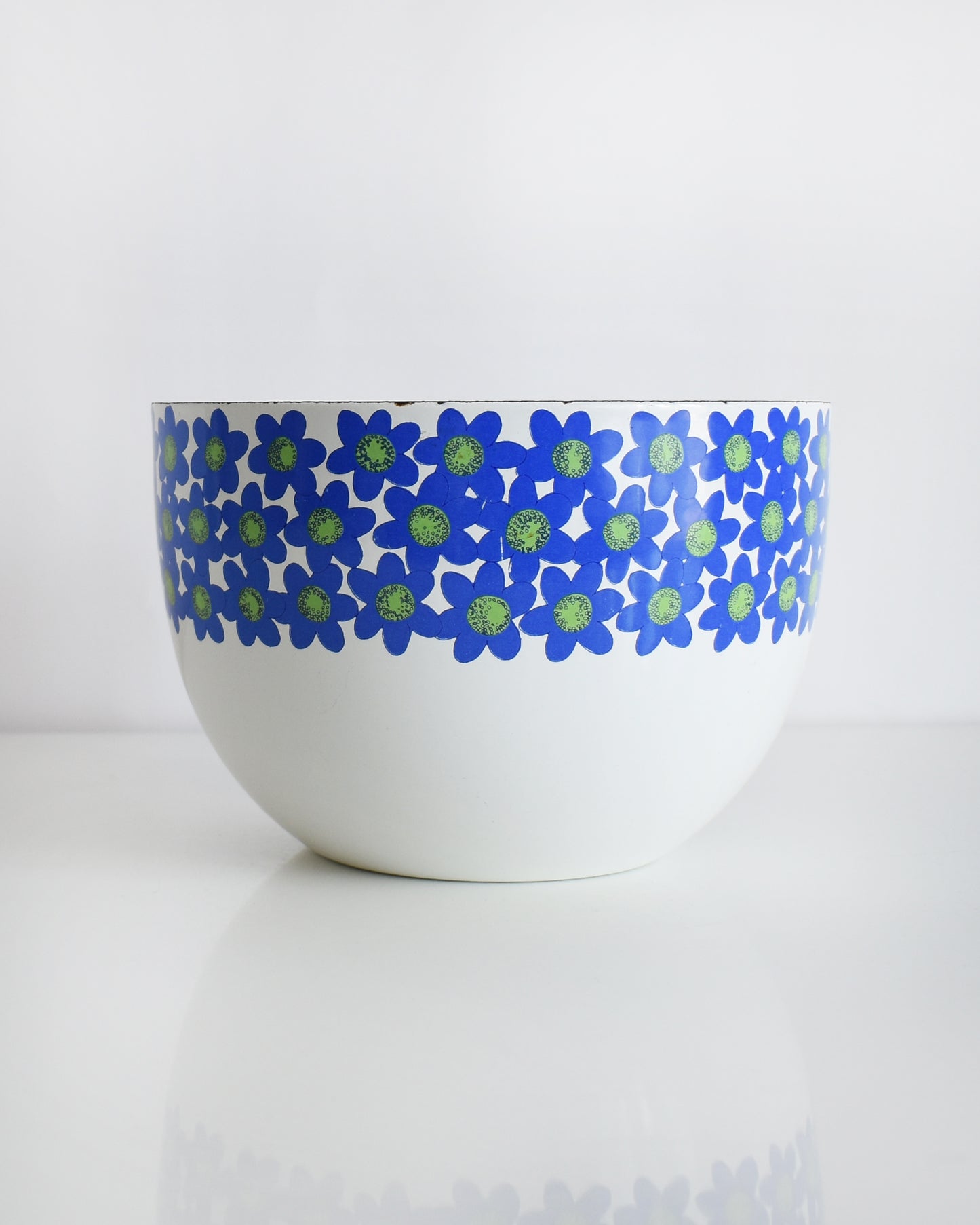 a vintage white 1970s Finel Arabia Finland bowl with blue and green flowers around the rim set against a clean white background.