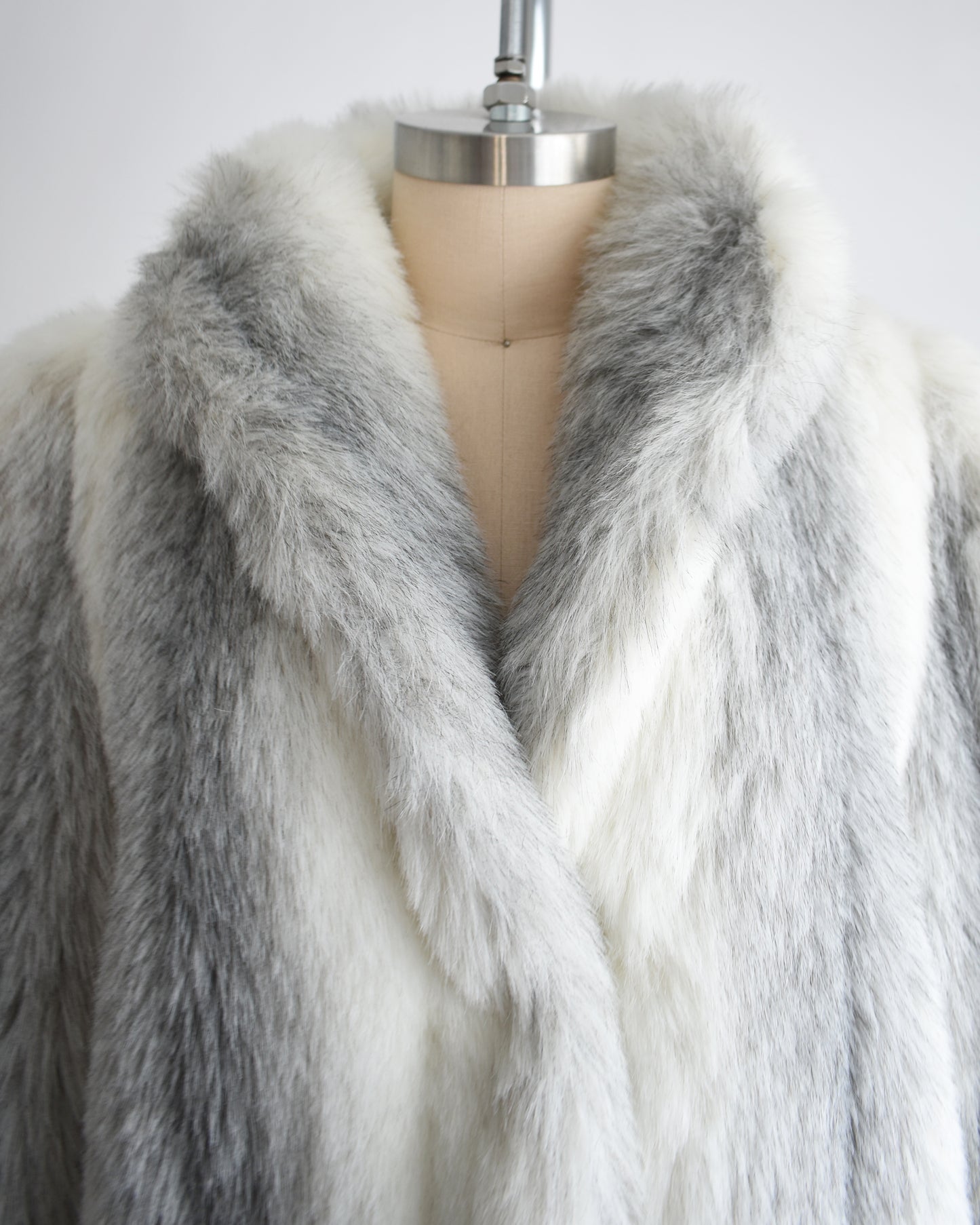 close up of the collar on a vintage 1980s faux fur coat on a mannequin against a white background