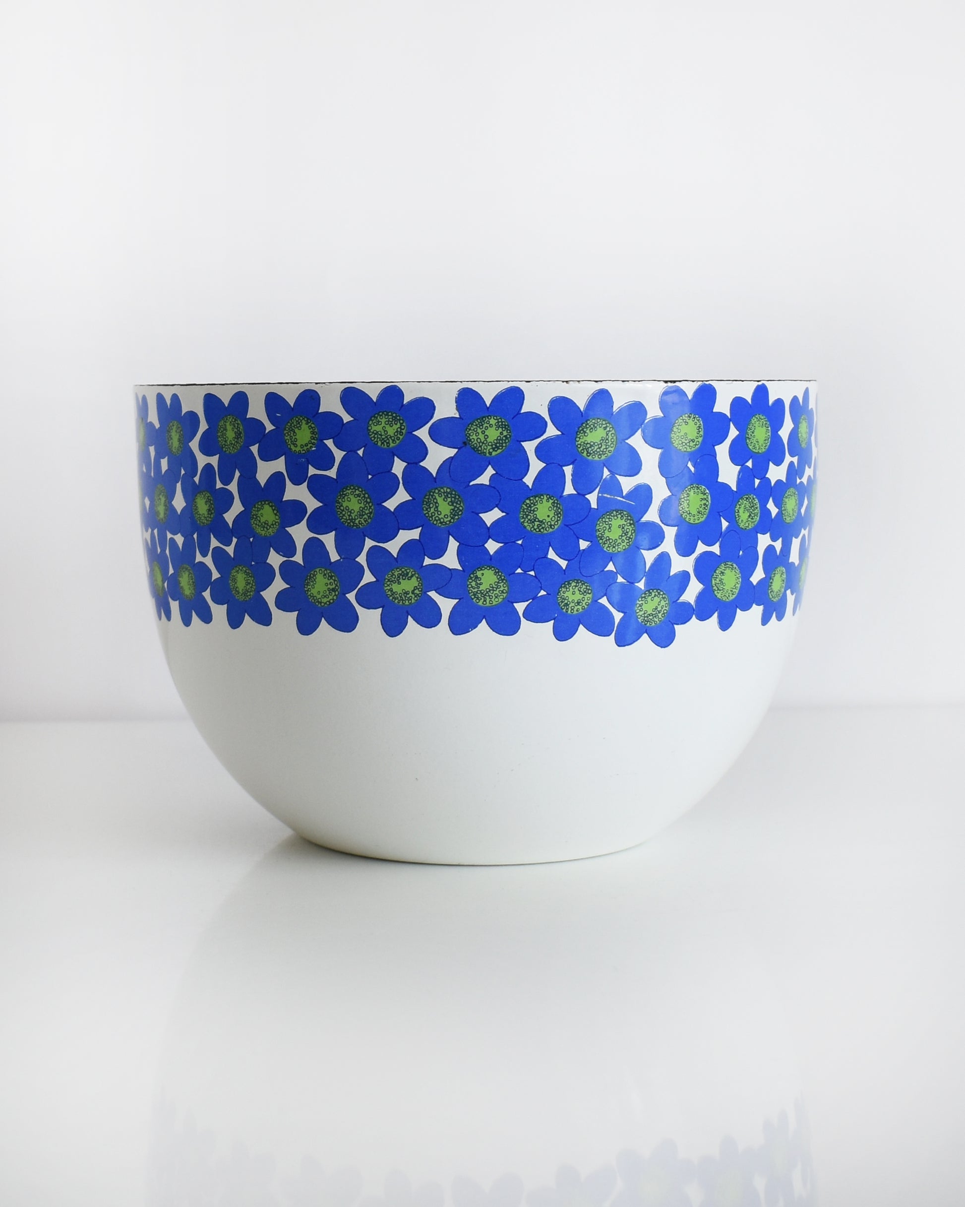 a vintage white 1970s Finel Arabia Finland bowl with blue and green flowers around the rim set against a clean white background.