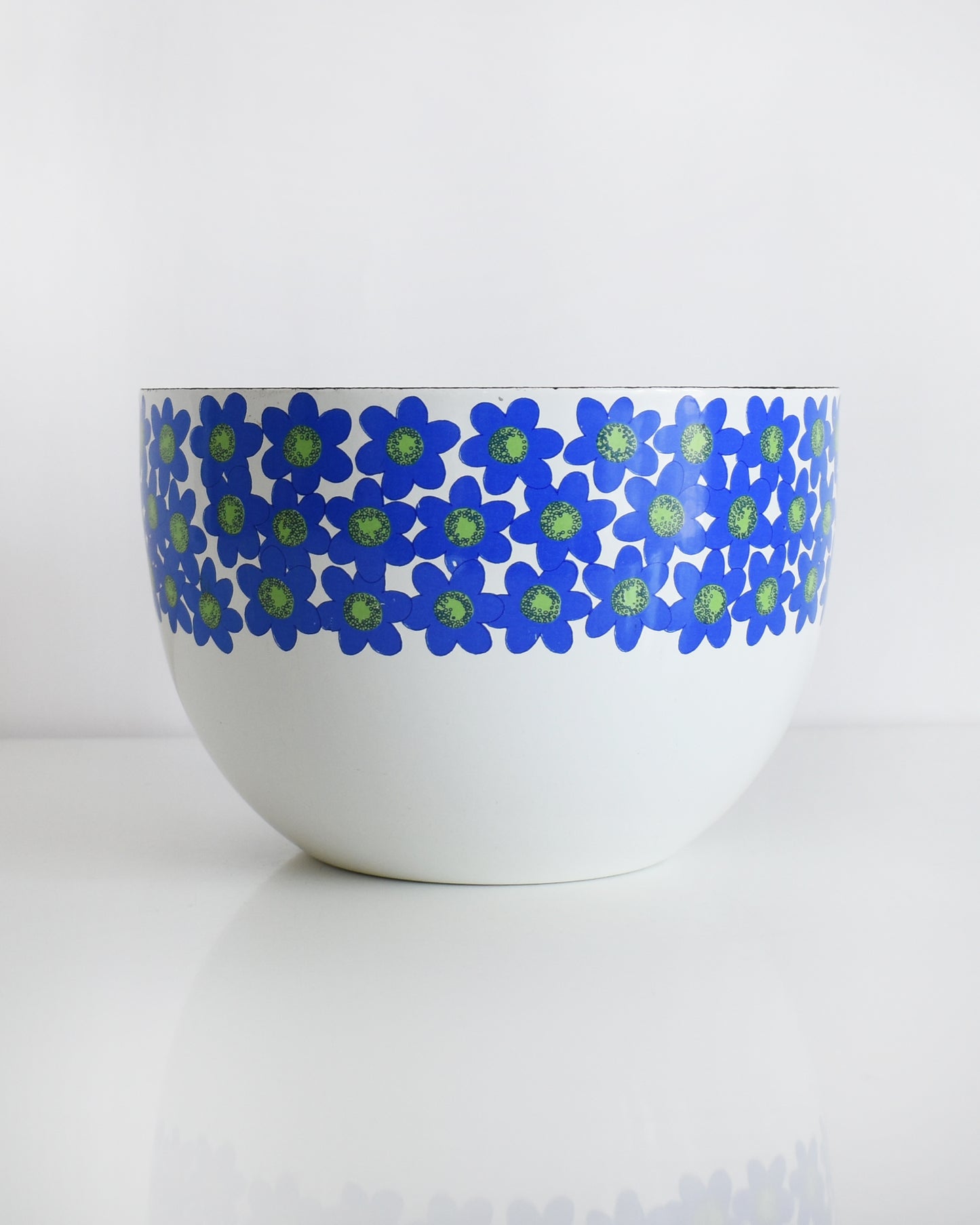 a vintage white 1970s Finel Arabia Finland bowl with blue and green flowers around the rim set against a clean white background.