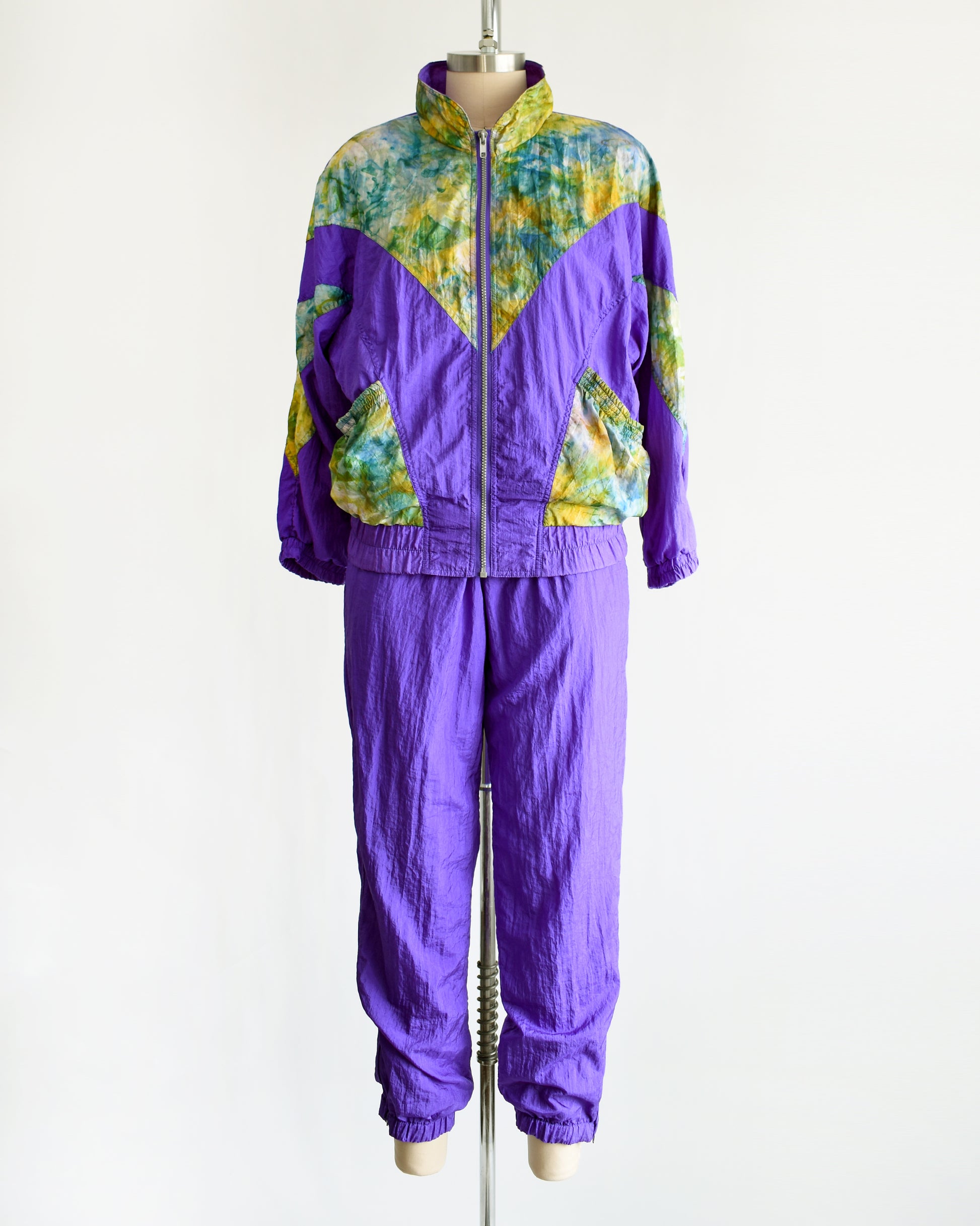 A vintage 1990s purple and multicolored tracksuit on a mannequin against a white background
