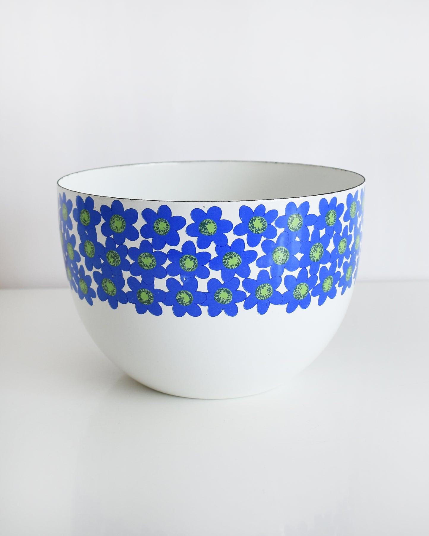 a vintage white 1970s Finel Arabia Finland bowl with blue and green flowers around the rim set against a clean white background.