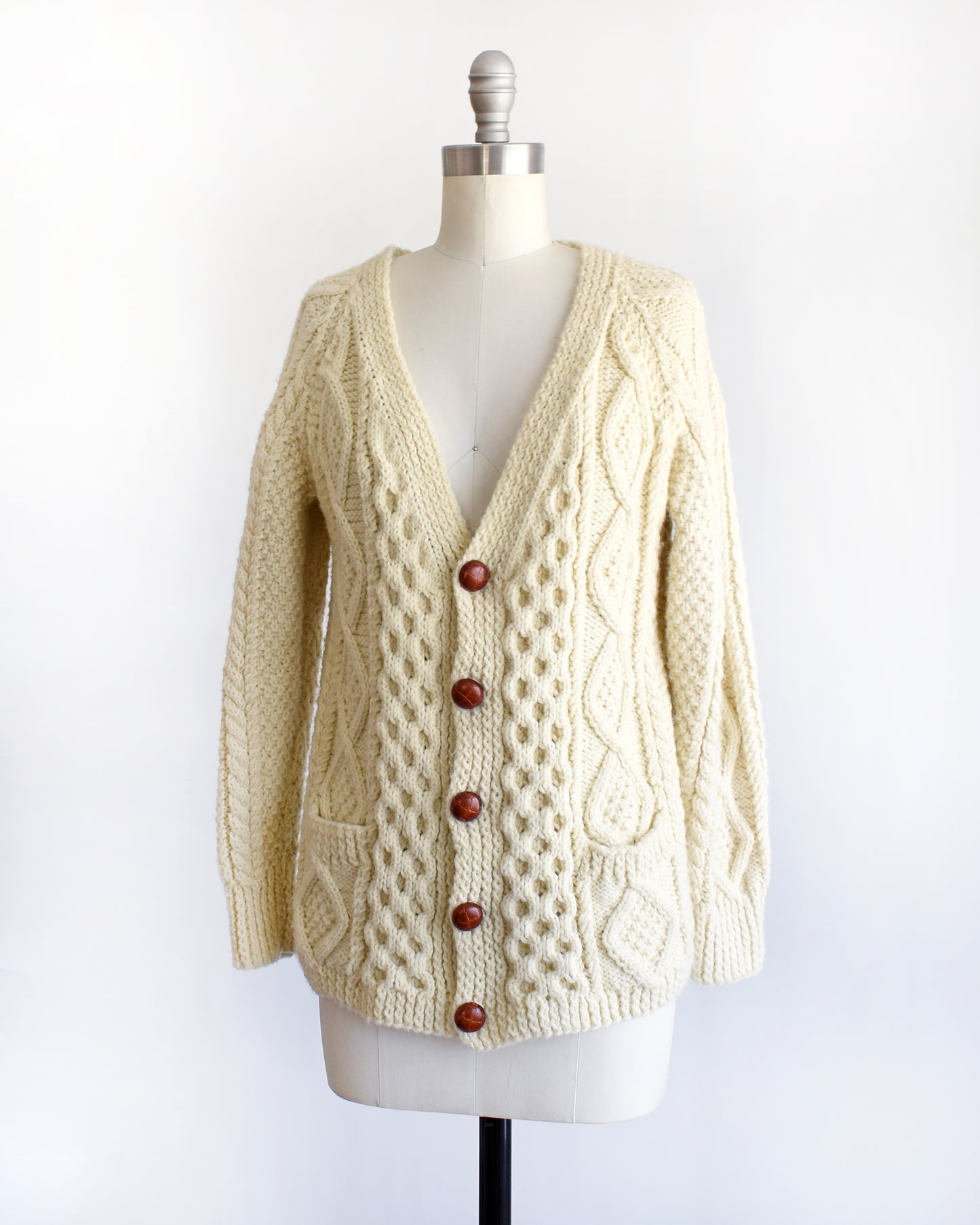 side front view of a vintage 1970s/1980s cream-colored cable knit cardigan on a mannequin against a white background