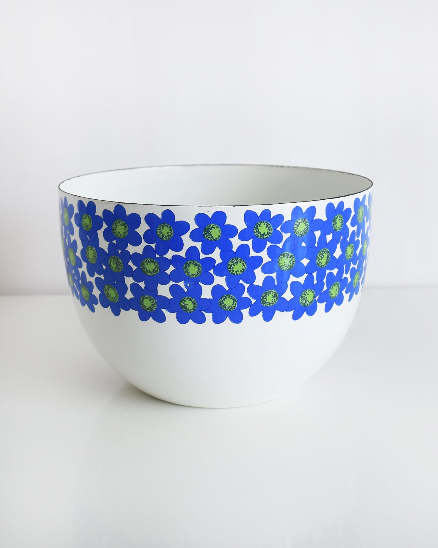 a vintage white 1970s Finel Arabia Finland bowl with blue and green flowers around the rim set against a clean white background.