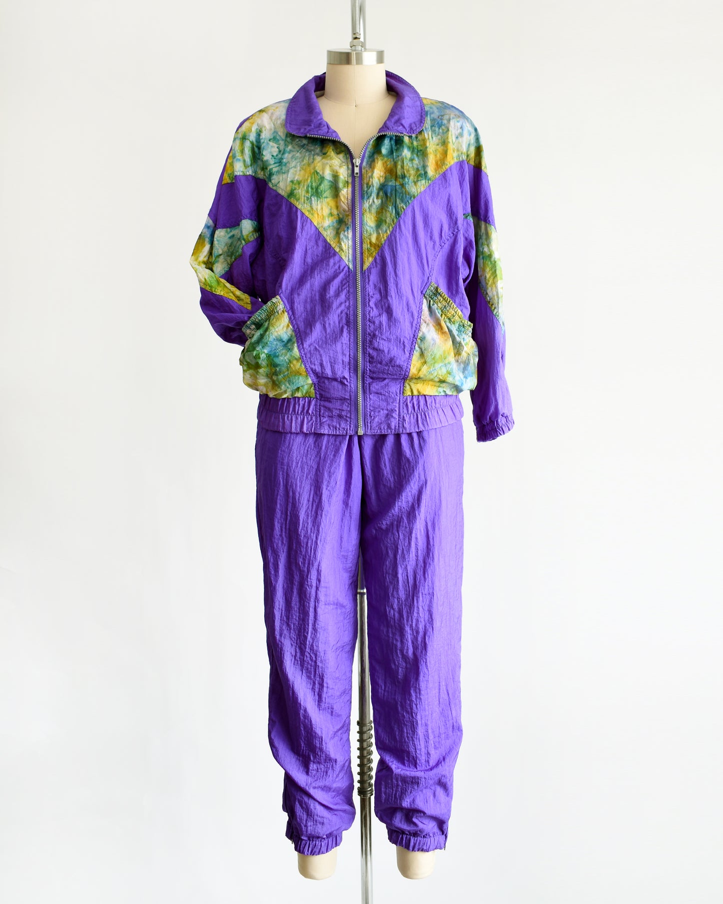 A vintage 1990s purple and multicolored tracksuit on a mannequin against a white background