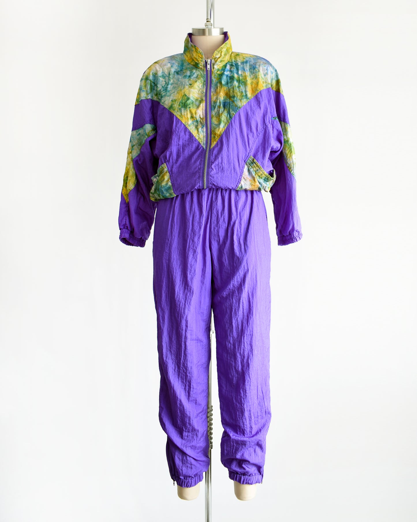 A vintage 1990s purple and multicolored tracksuit on a mannequin against a white background