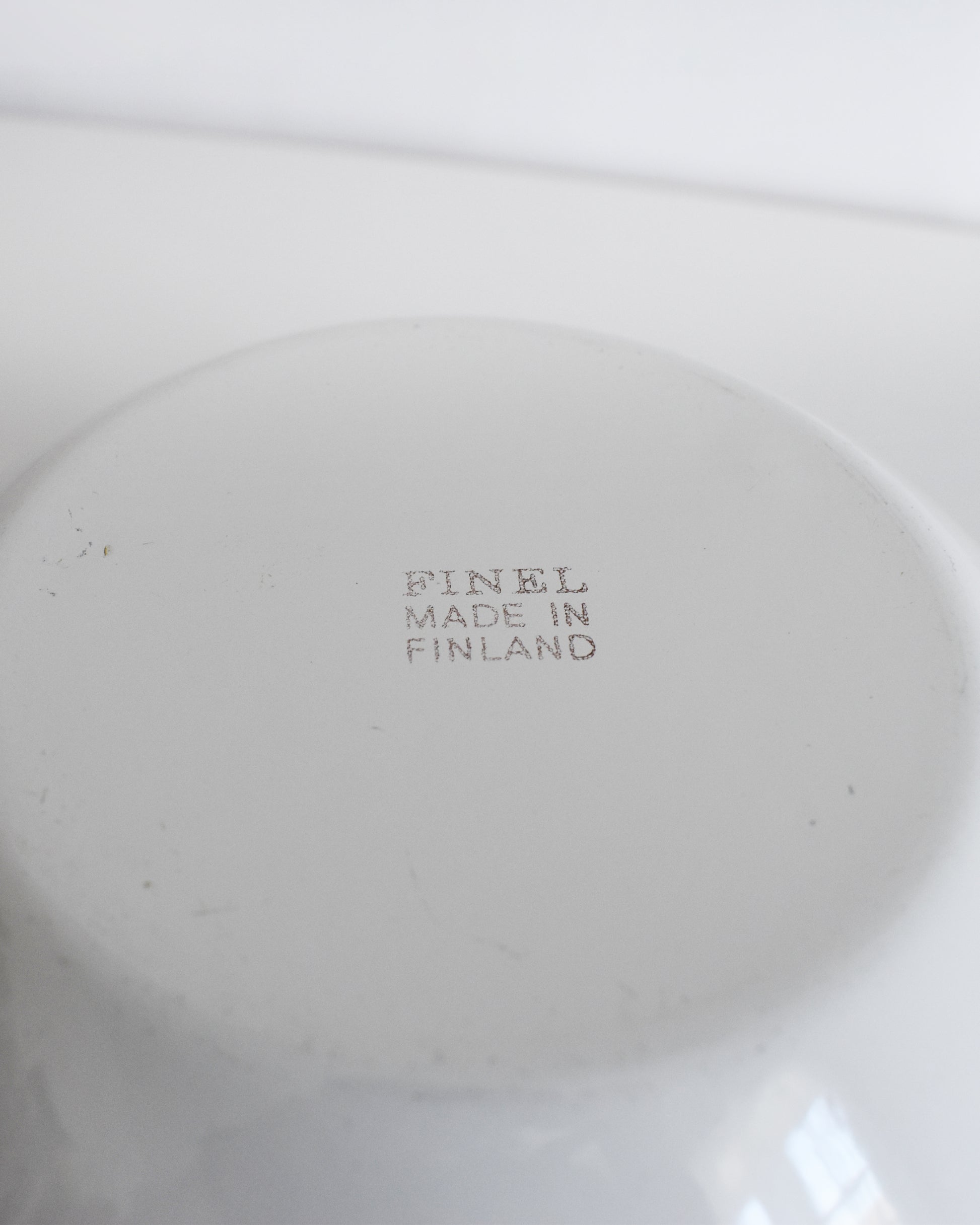 Close-up of the bottom of a white bowl with the stamped text 'FINEL MADE IN FINLAND' in the center.