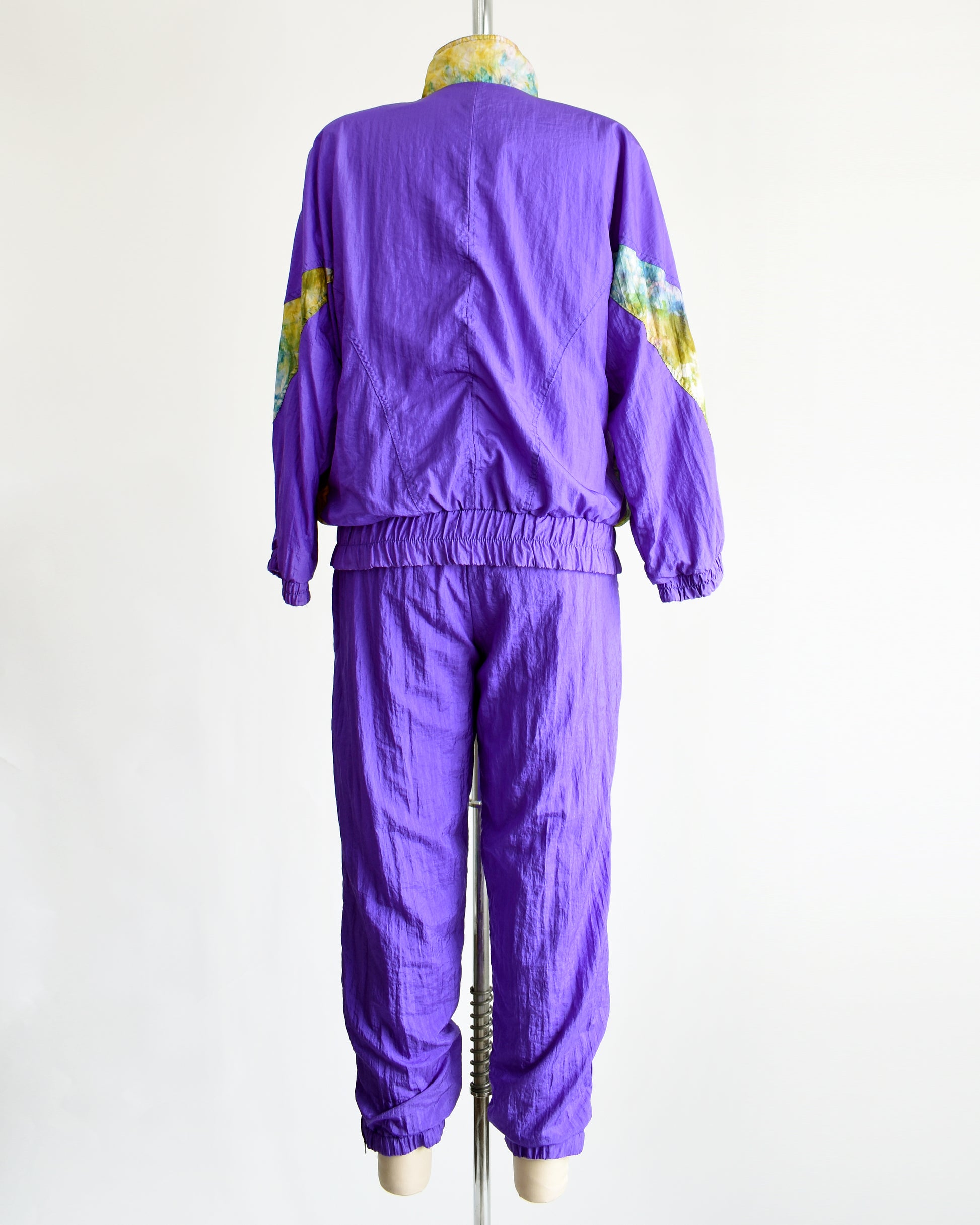 back view of a vintage 1990s purple and multicolored tracksuit on a mannequin against a white background