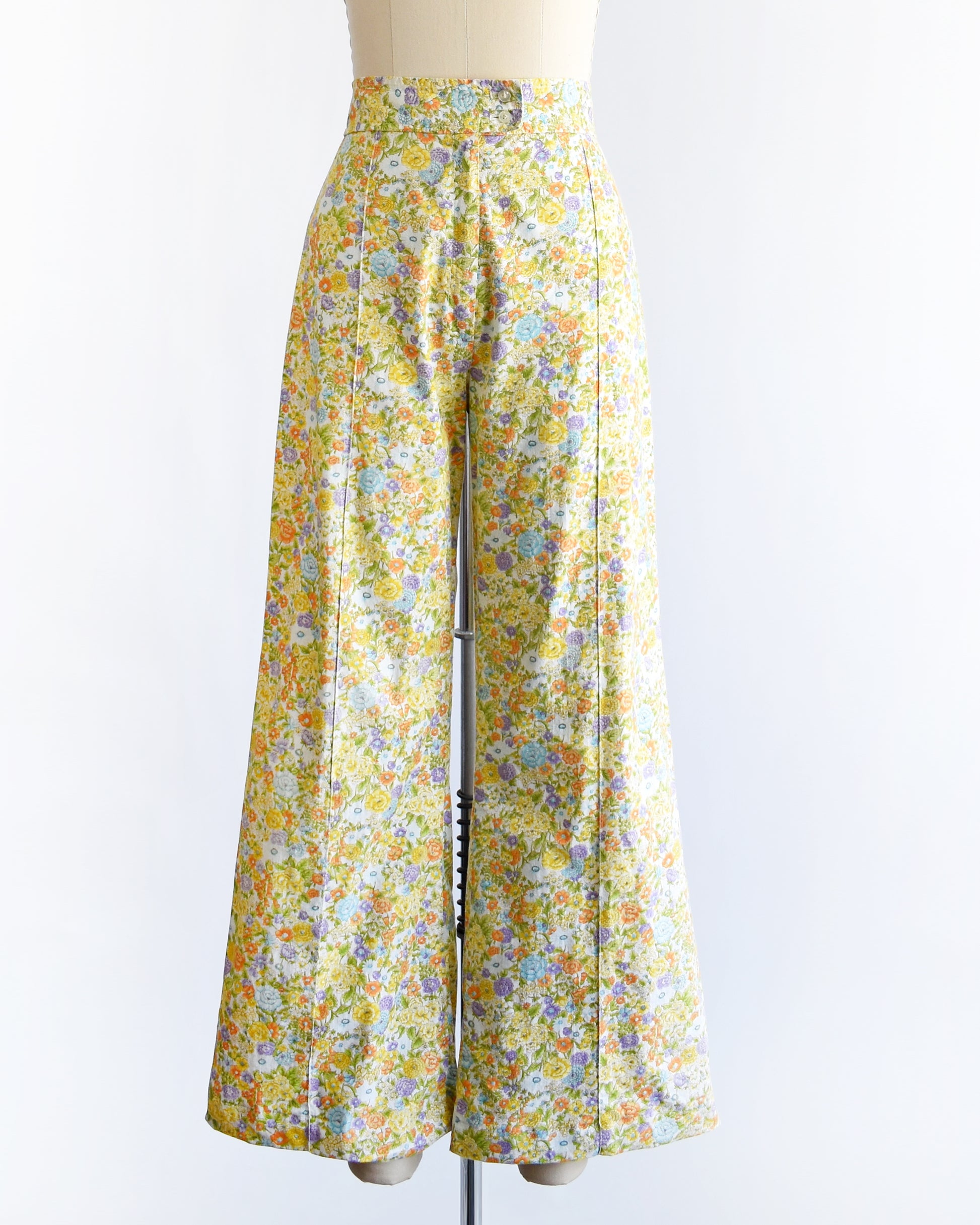 vintage 1970s yellow floral wide-leg pants displayed on a beige dress form mannequin against a white studio background.