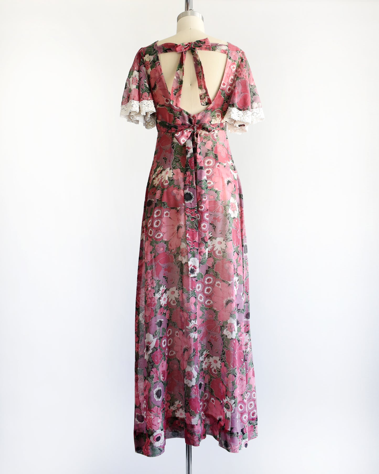 back view of a vintage 1970s floral dress on a mannequin against a white background
