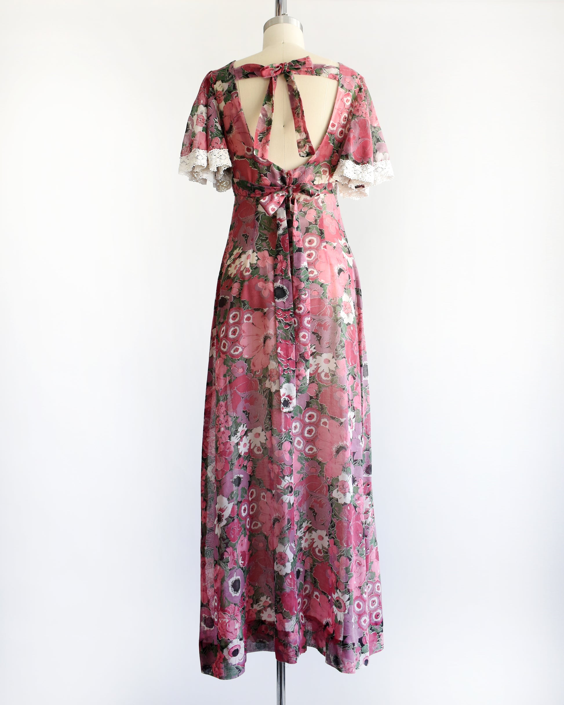 back view of a vintage 1970s floral dress on a mannequin against a white background