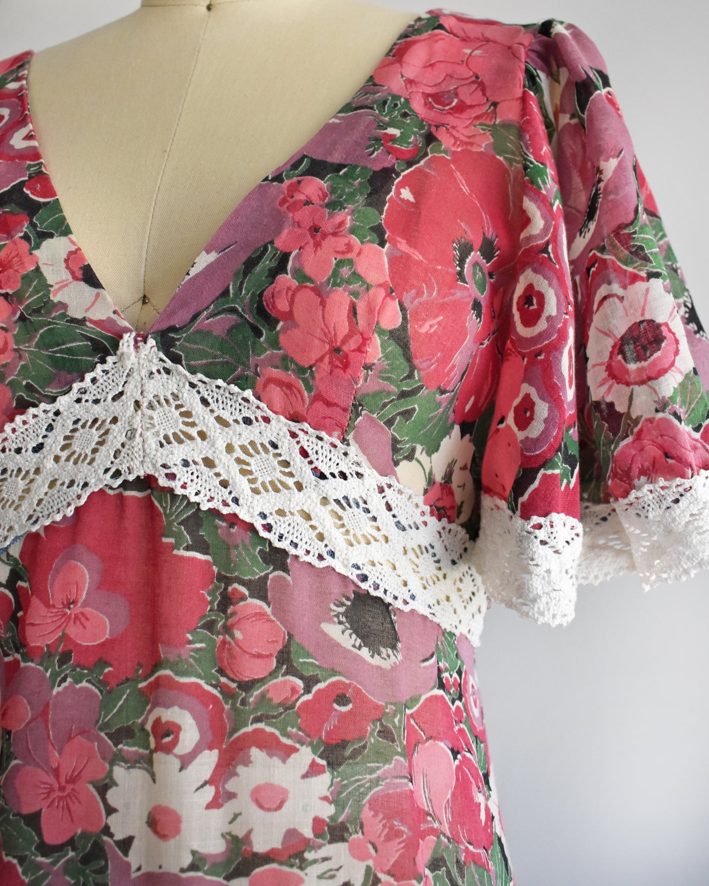 close up of the bodice on a vintage 1970s floral dress on a mannequin against a white background