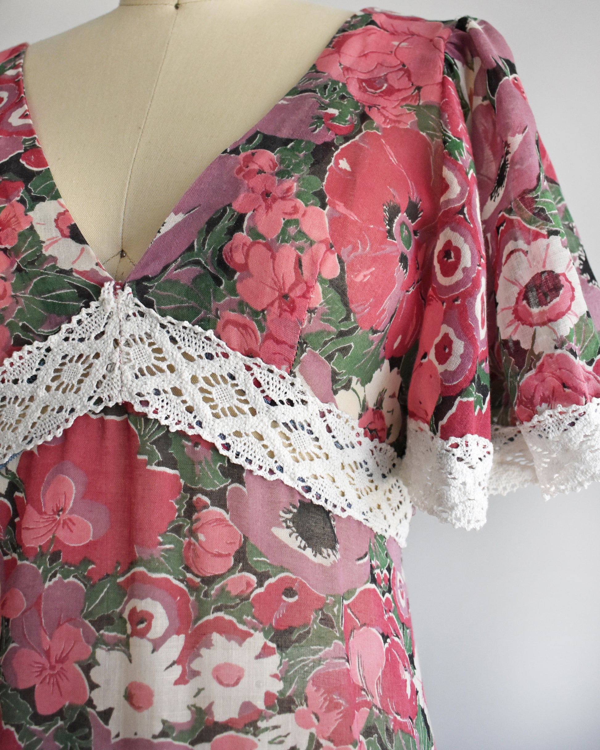 close up of the bodice of a vintage 1970s floral dress on a mannequin against a white background