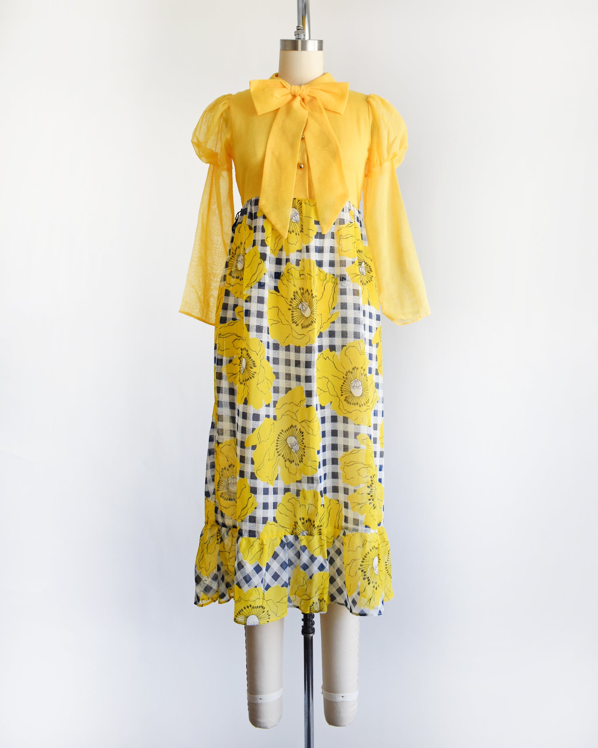 a vintage 1960s 1970s yellow and black floral dress on a mannequin against a white background