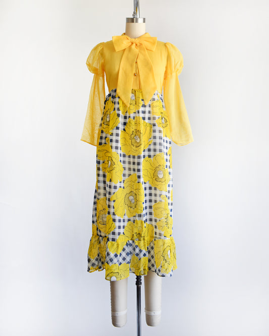 a vintage 1960s 1970s yellow and black floral dress on a mannequin against a white background
