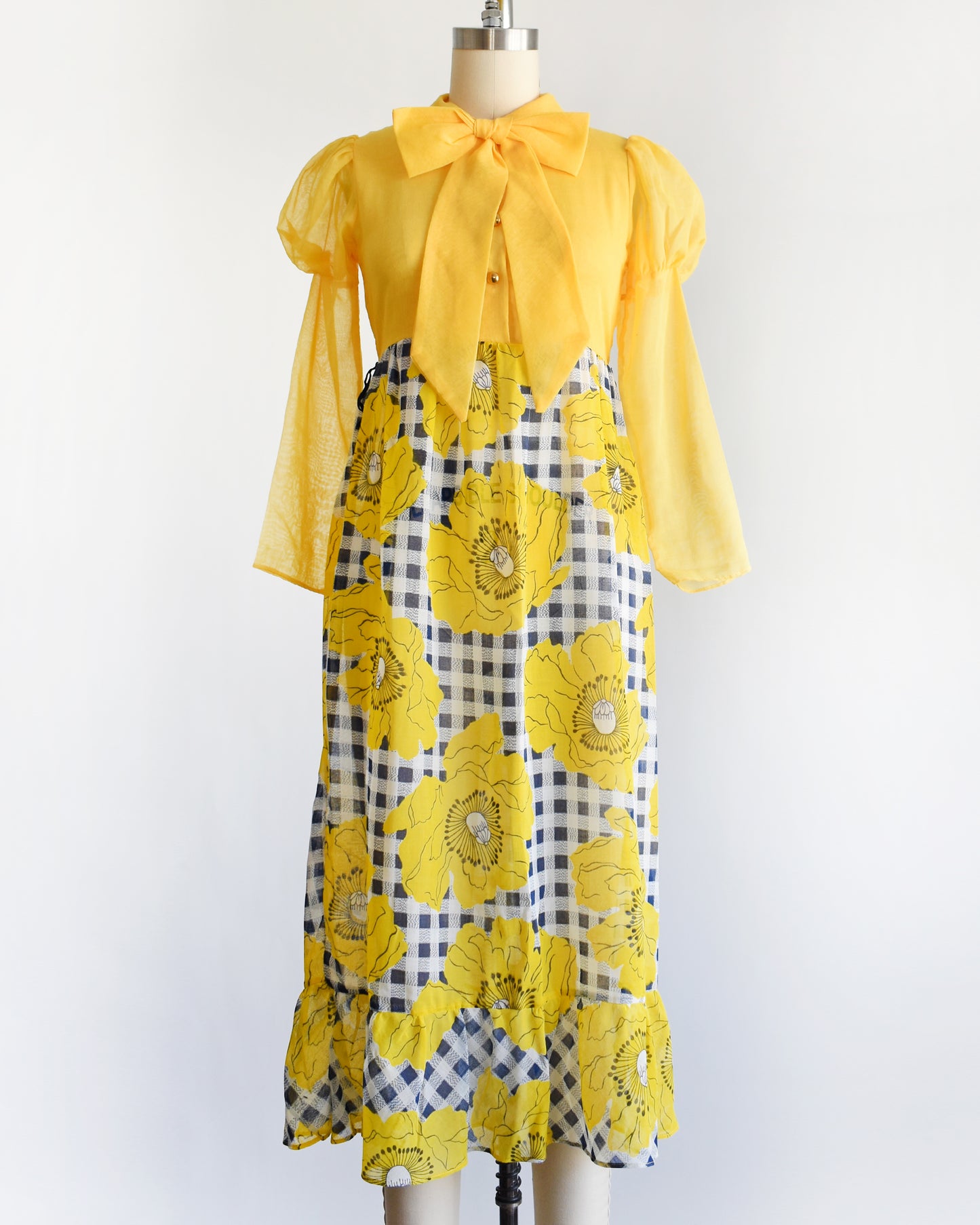 a vintage 1960s 1970s yellow and black floral dress on a mannequin against a white background