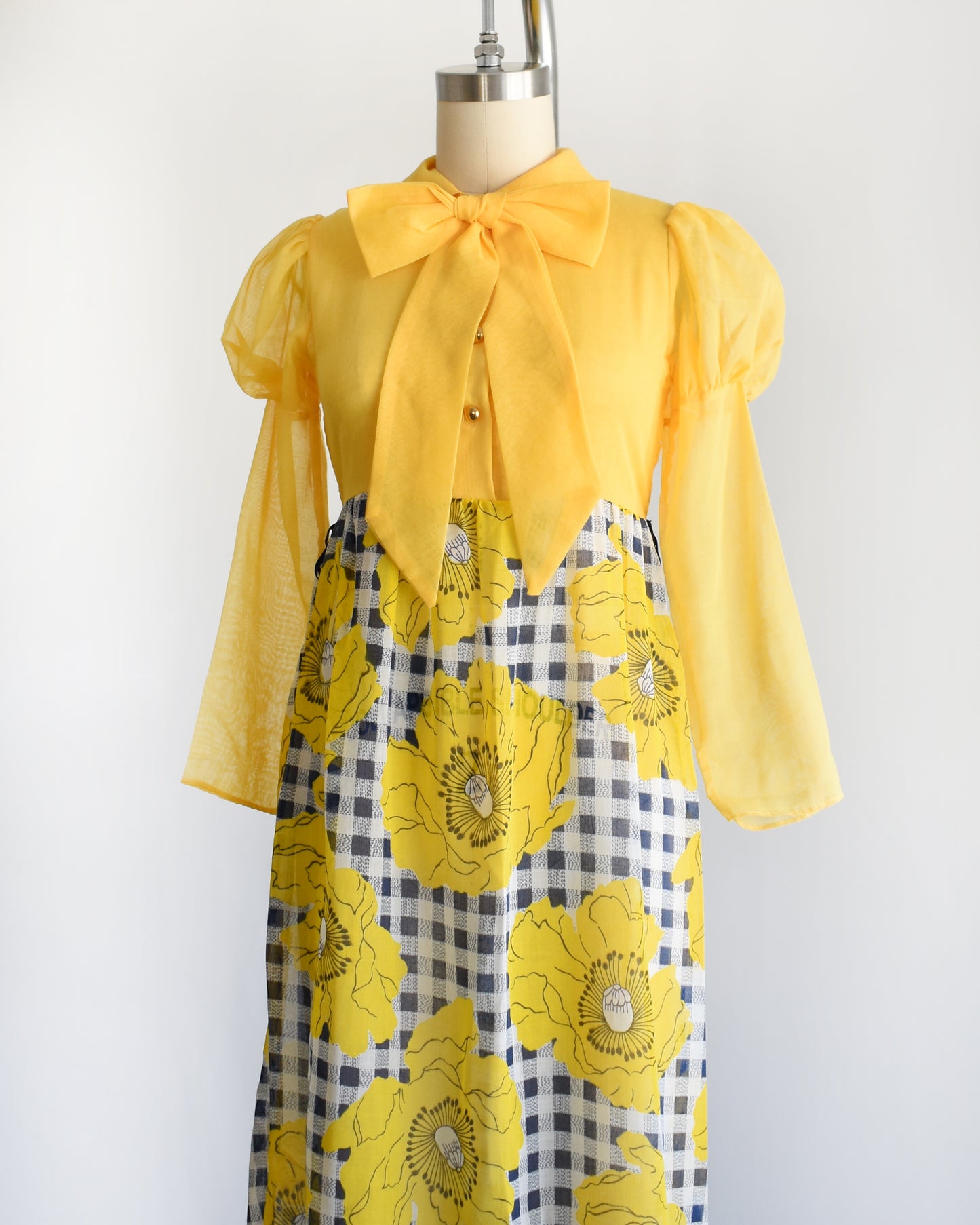 side front view of a vintage 1960s 1970s yellow and black floral dress on a mannequin against a white background