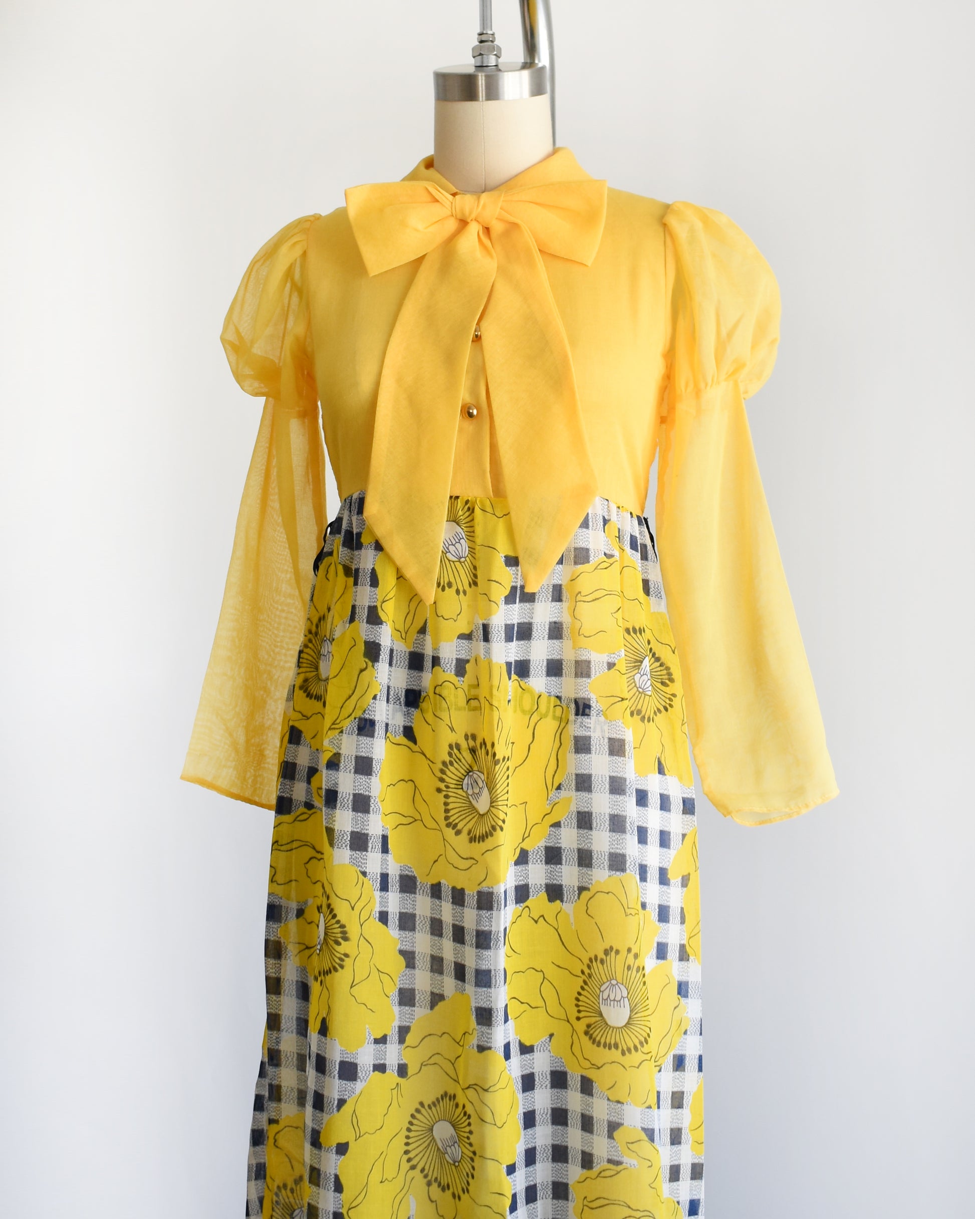 side front view of a vintage 1960s 1970s yellow and black floral dress on a mannequin against a white background
