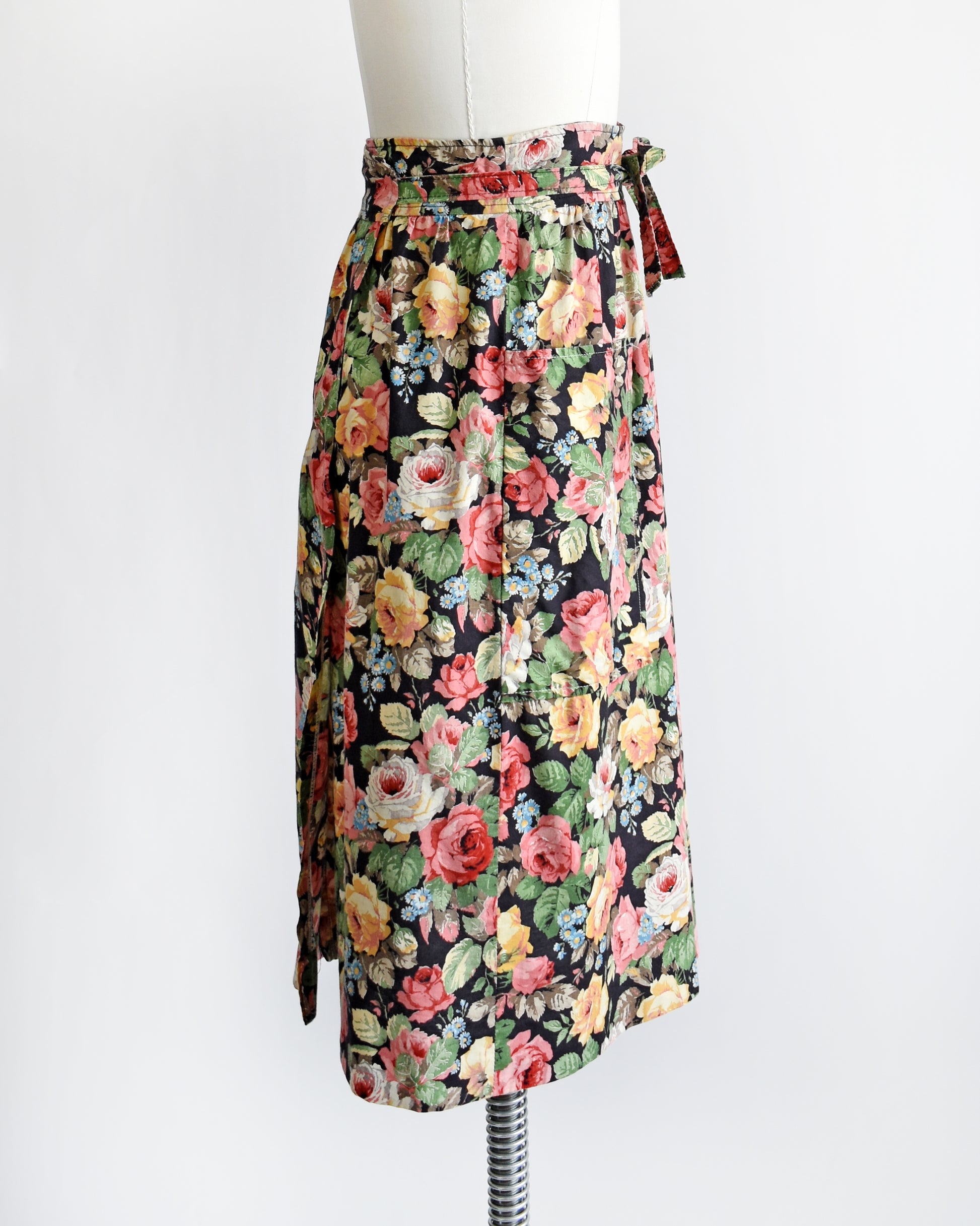 side view of a vintage 1970s black floral wrap skirt that has two large pockets on the front