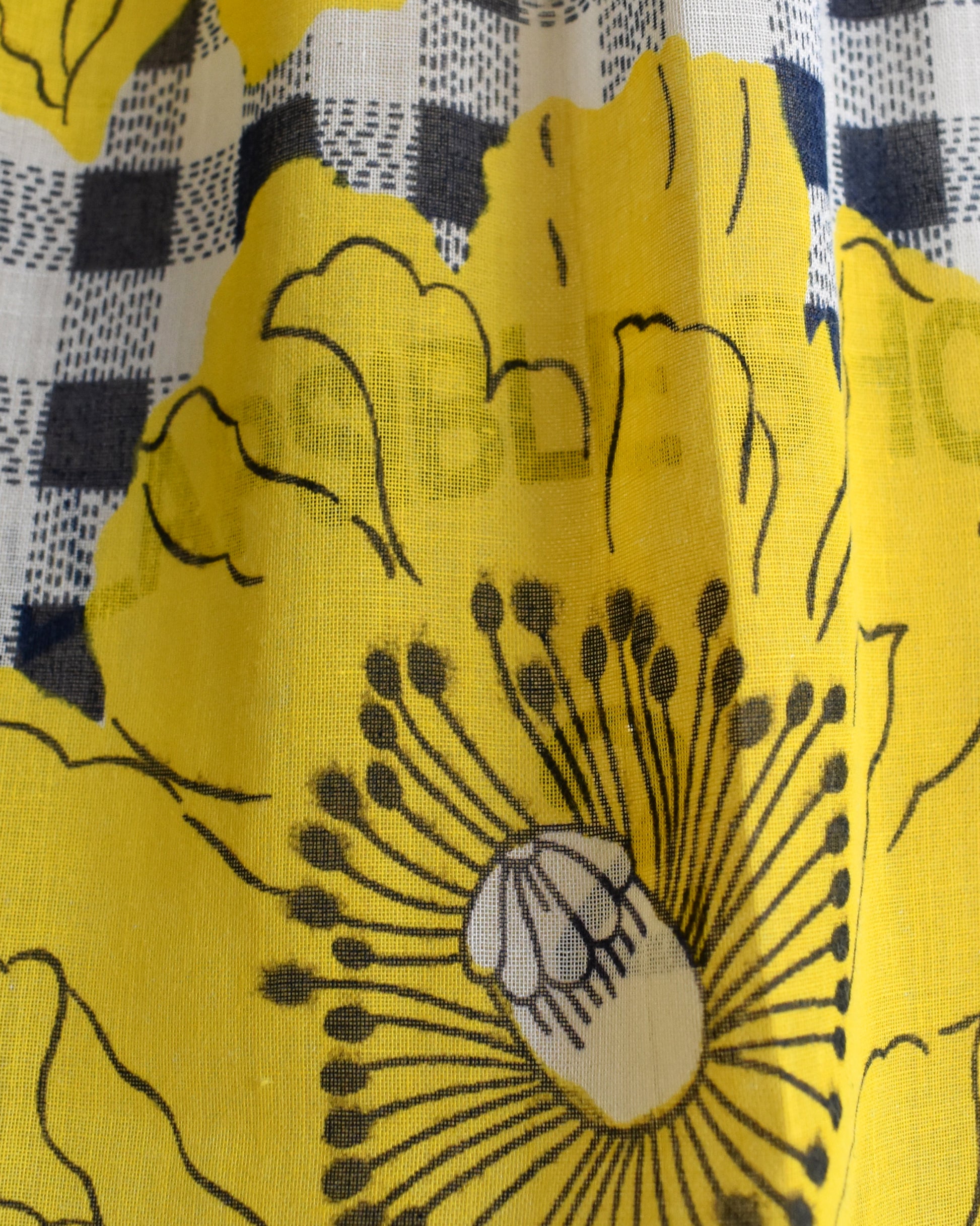 Close-up of yellow fabric with black floral pattern on a checkered background