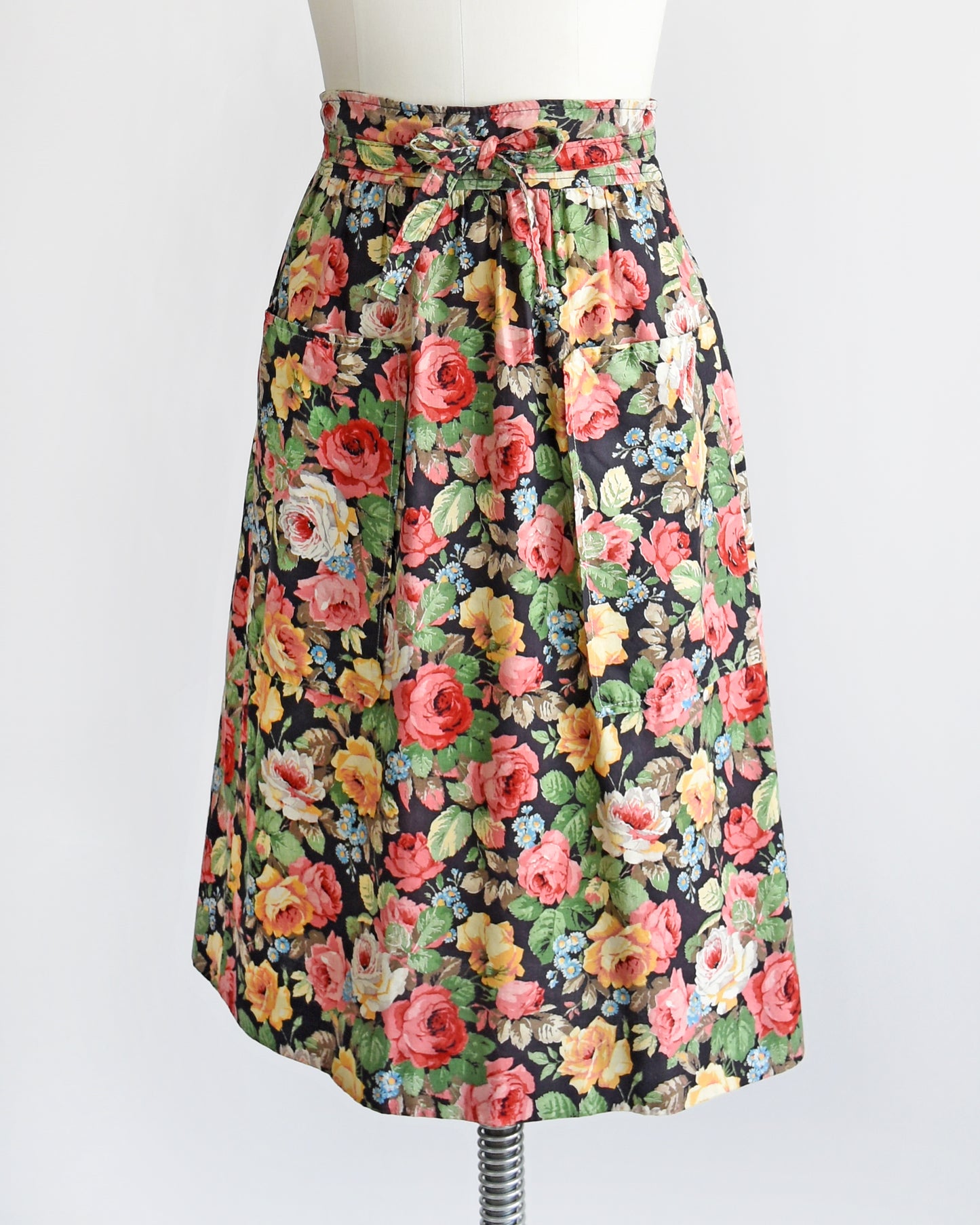 side front view of a vintage 1970s black floral wrap skirt that has two large pockets on the front