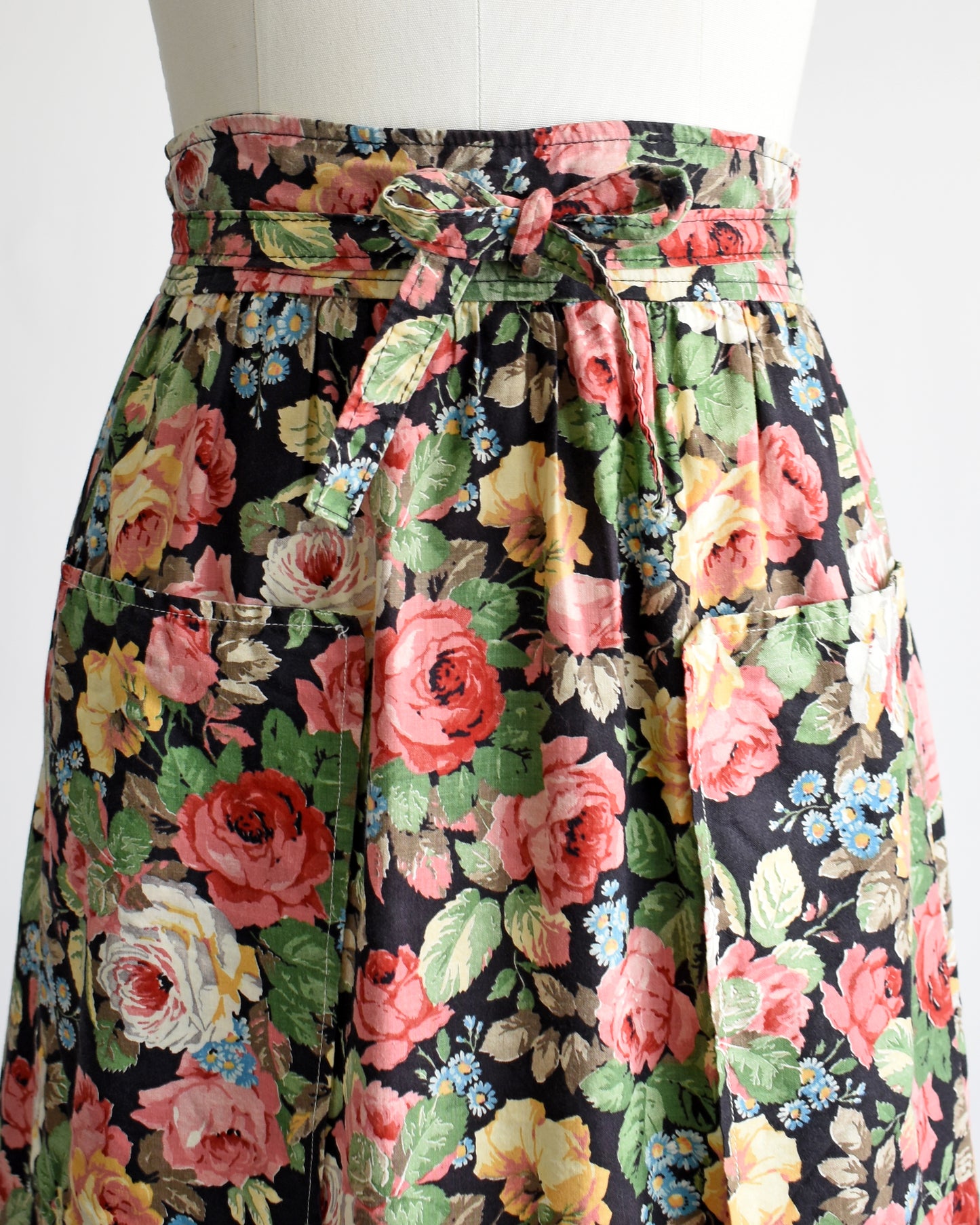 close up of the waist which shows the ties that are wrapped in a bow, the patch pockets, and the floral print