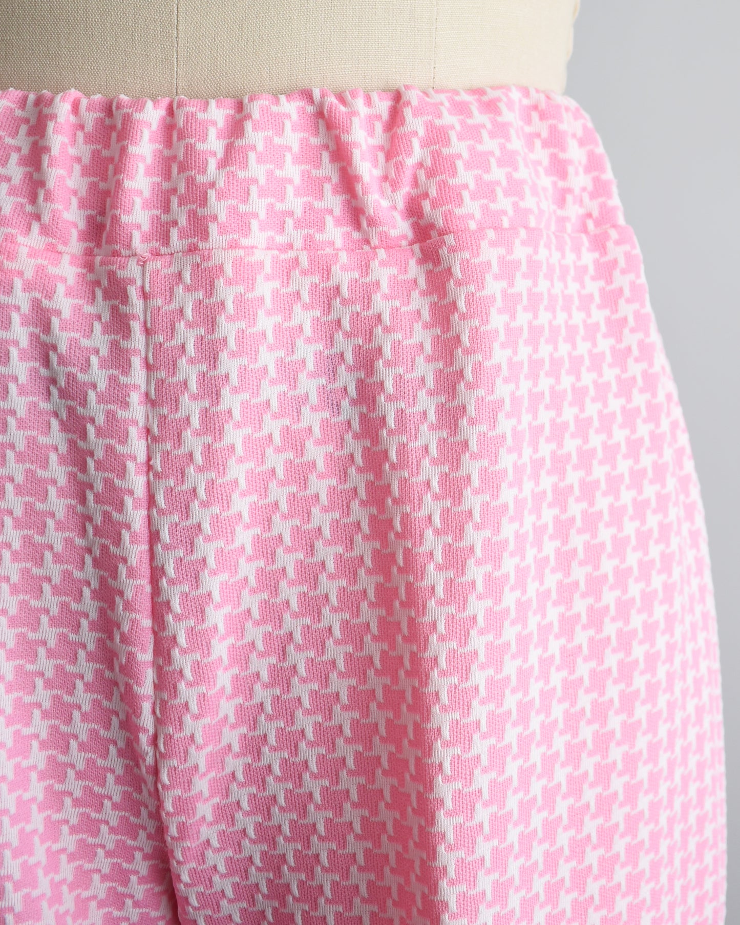 Close up of the elastic waist and houndstooth print on a pair of pink and white vintage 1970s pants