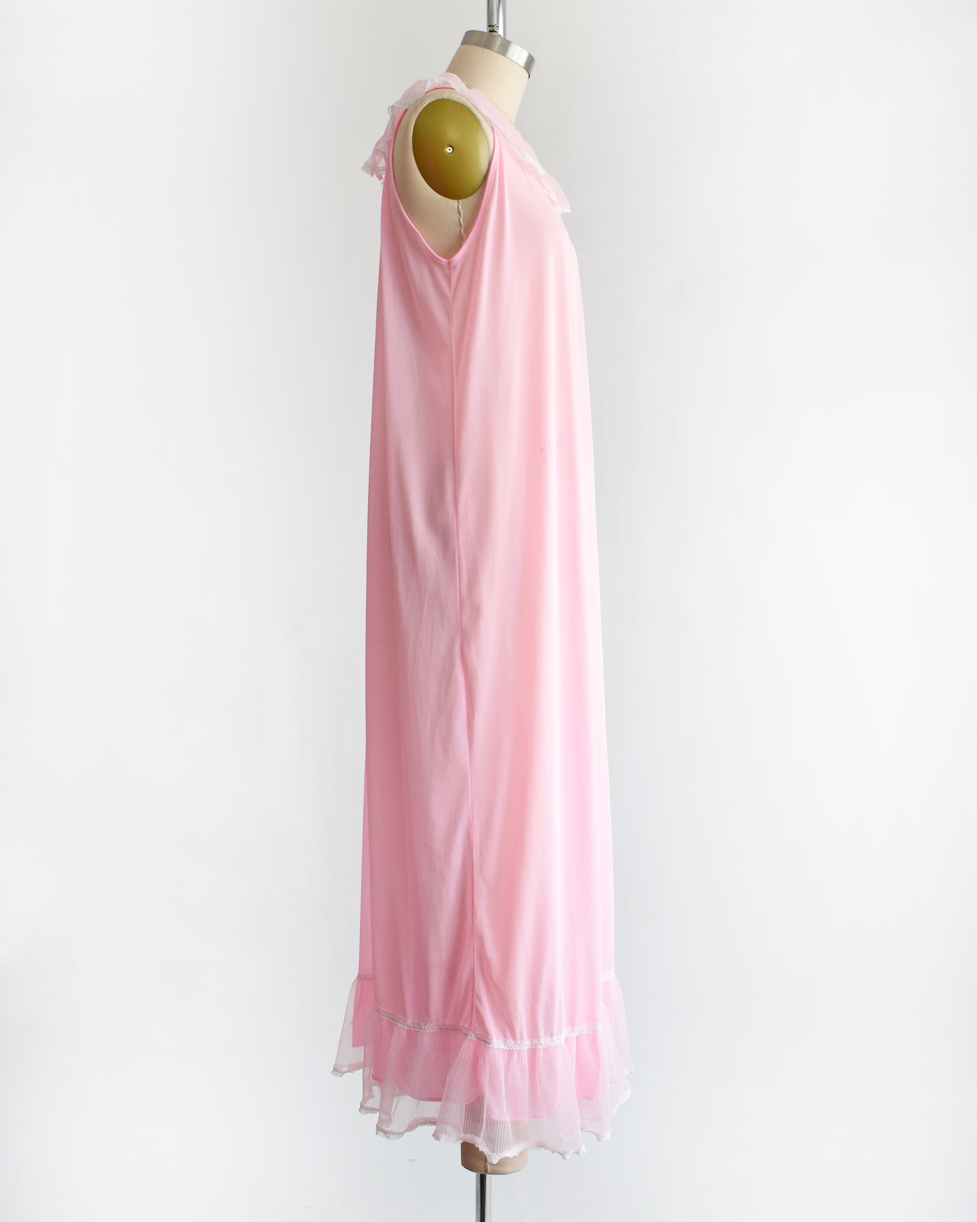 side view of a vintage 1970s sleeveless pink nightgown with a ruffled collar and hem, displayed on a dress form against a plain white background.