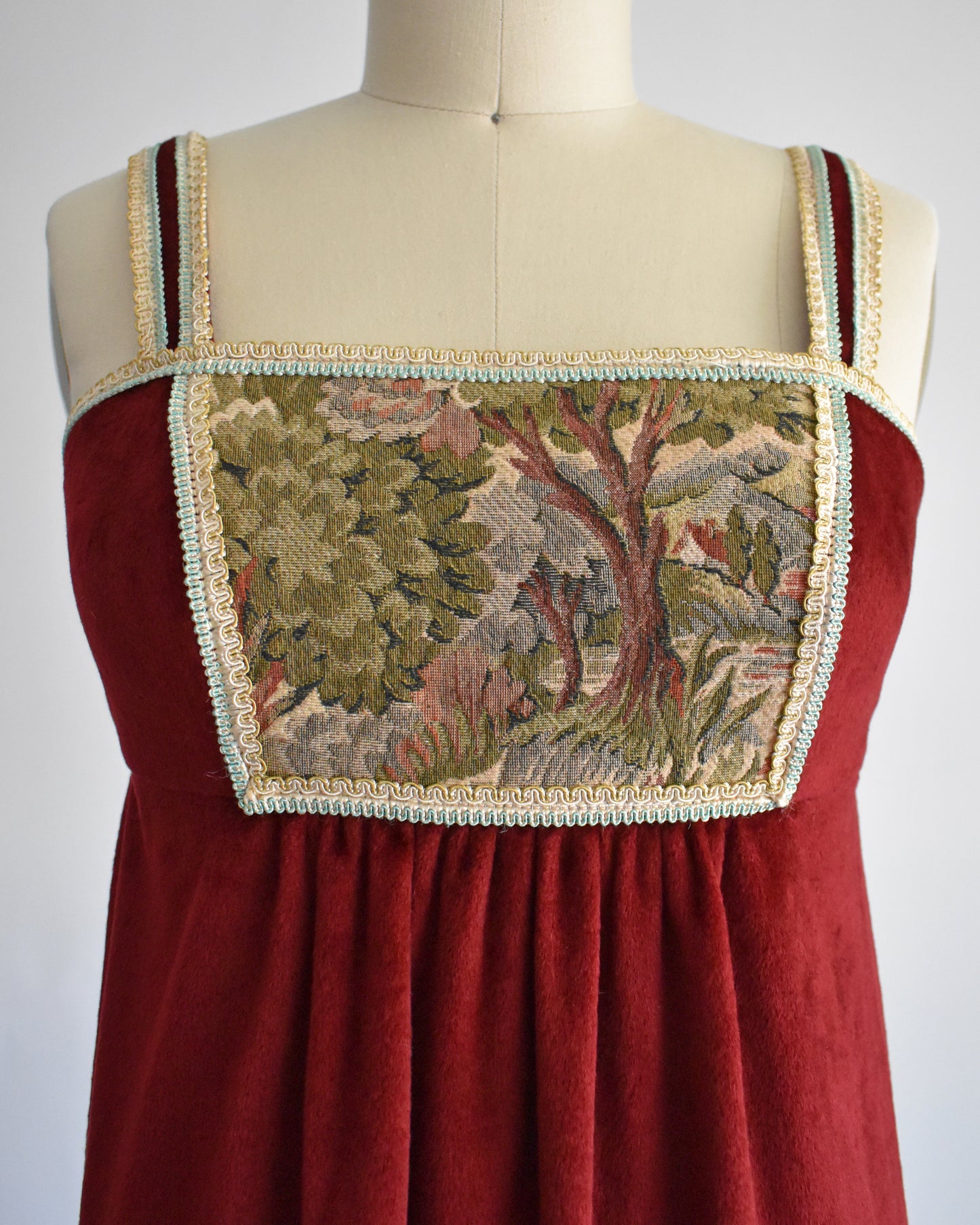 close up of the tapestry on the bodice of the dress which depicts a woodsy scene