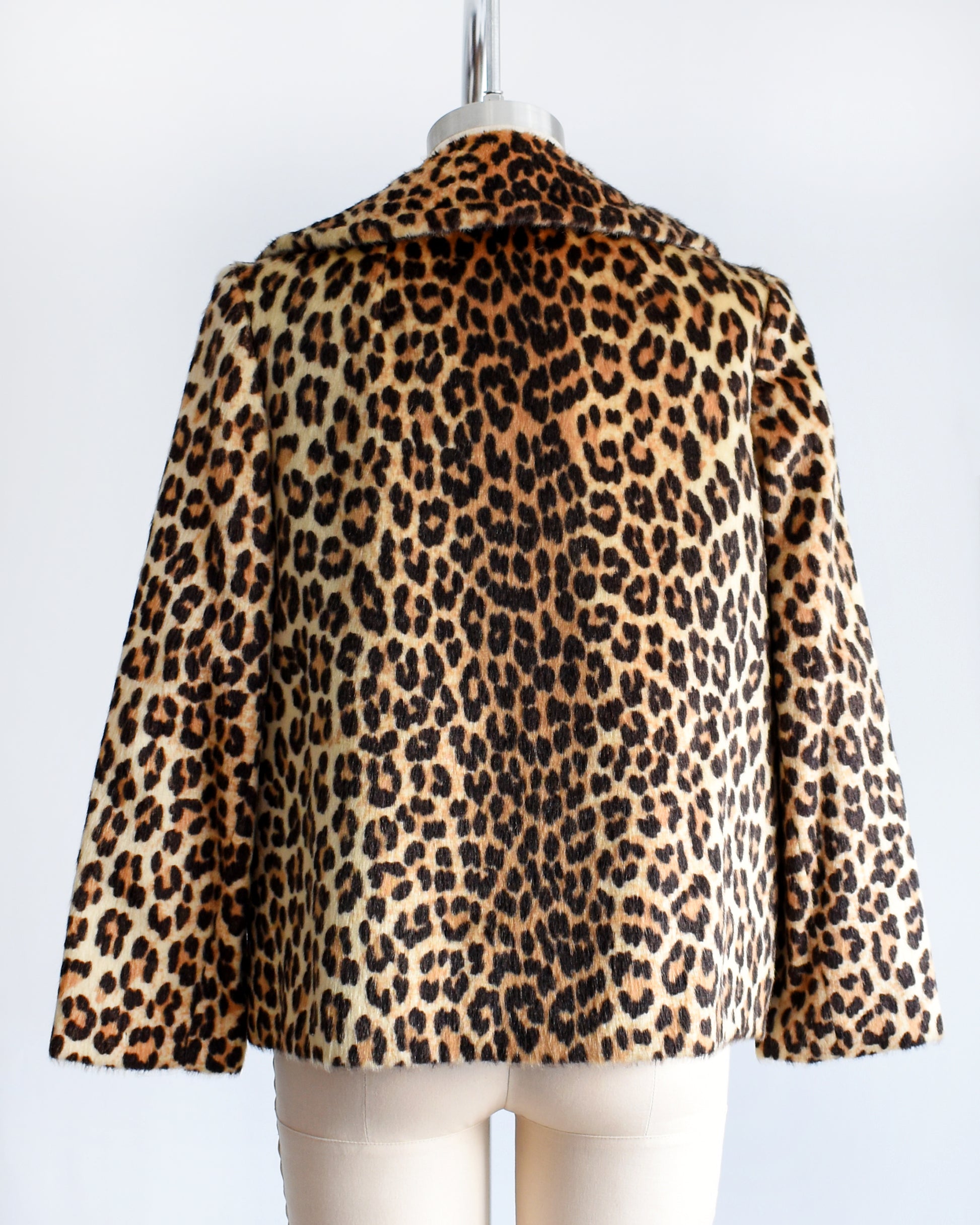 back view of a vintage 1960s leopard print jacket on a mannequin against a white background