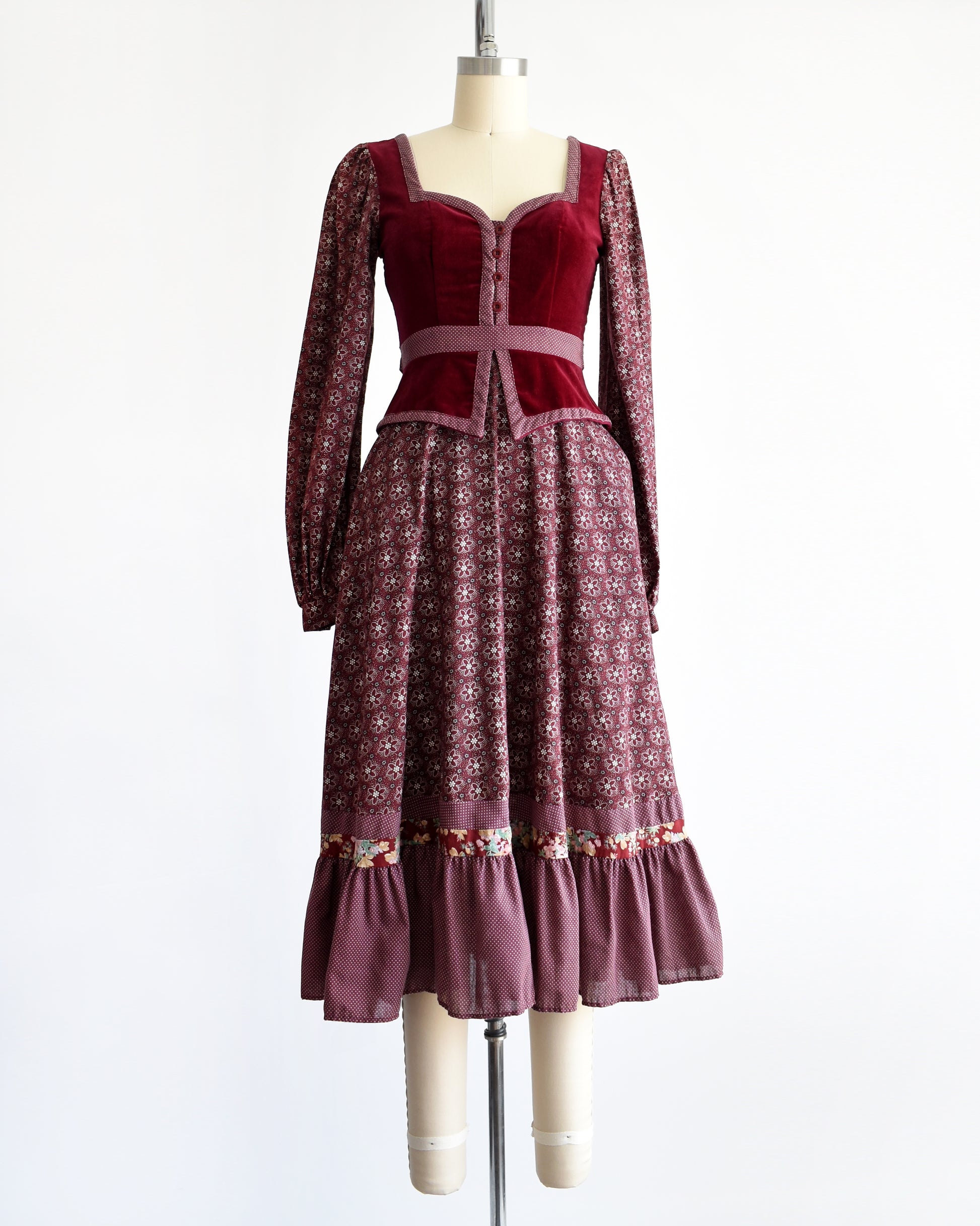 a vintage 1970s Gunne Sax dress that is burgundy and has a velvet bodice and floral skirt and long sleeves