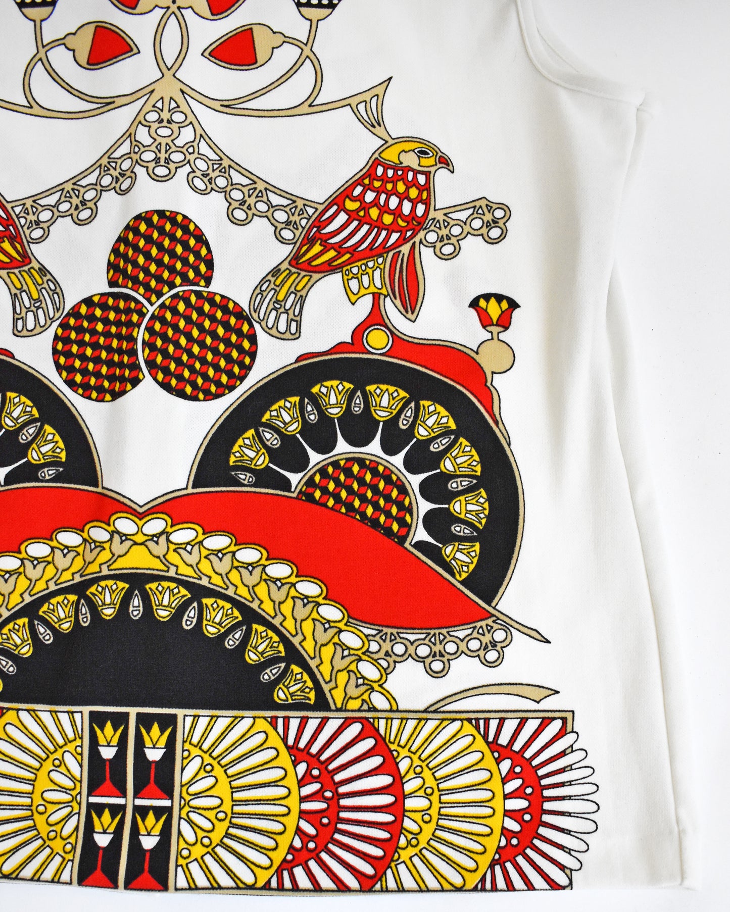 Close-up of a colorful patterned fabric with birds and geometric designs on a white background.