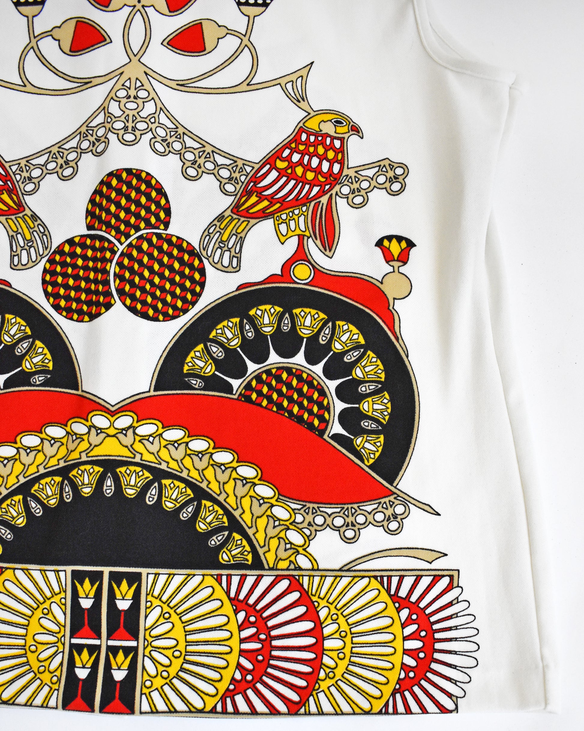 Close-up of a colorful patterned fabric with birds and geometric designs on a white background.