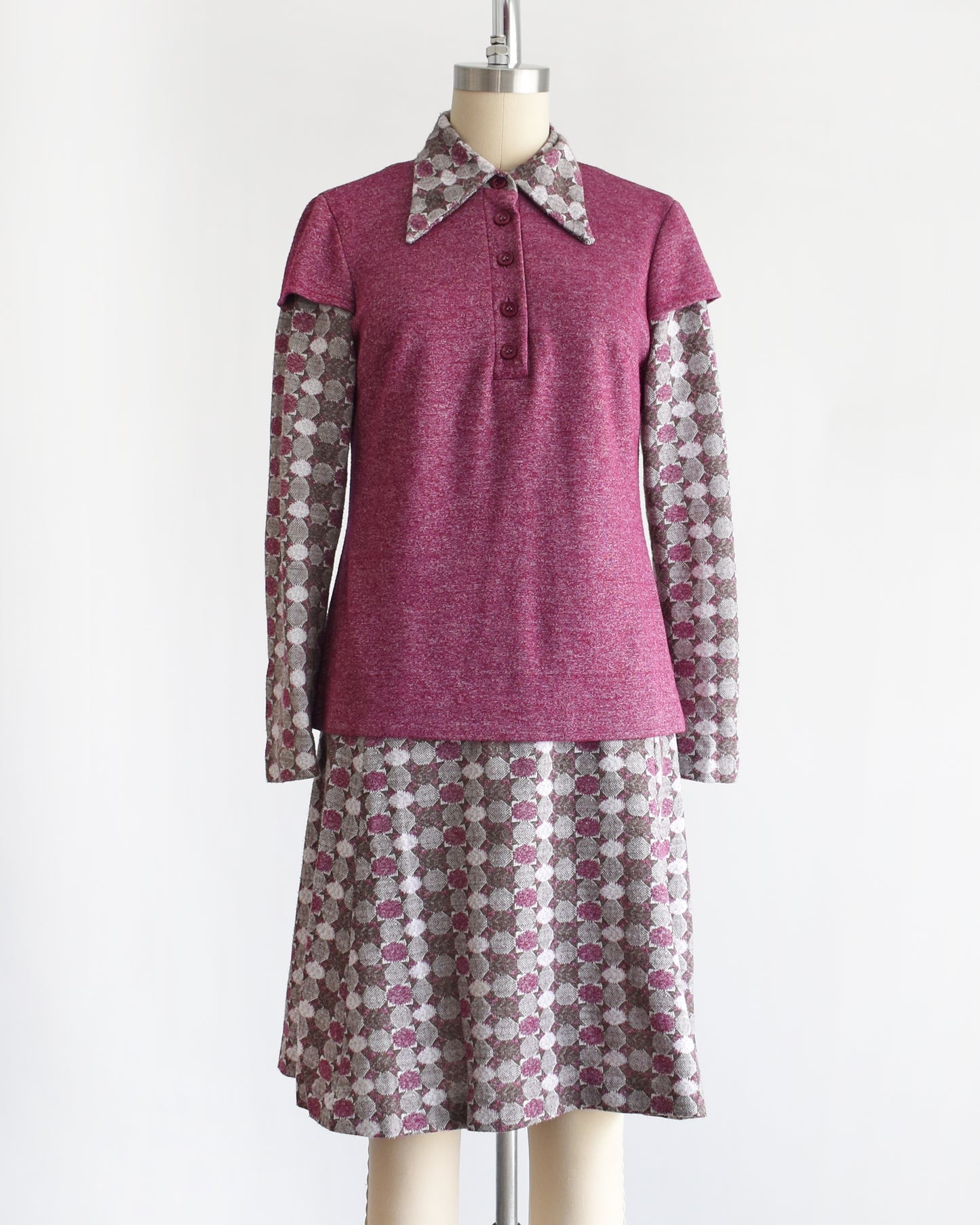 a vintage 1970s dress set that has a purple top and patterned skirt on a mannequin against a white background. the top is untucked in the photo.