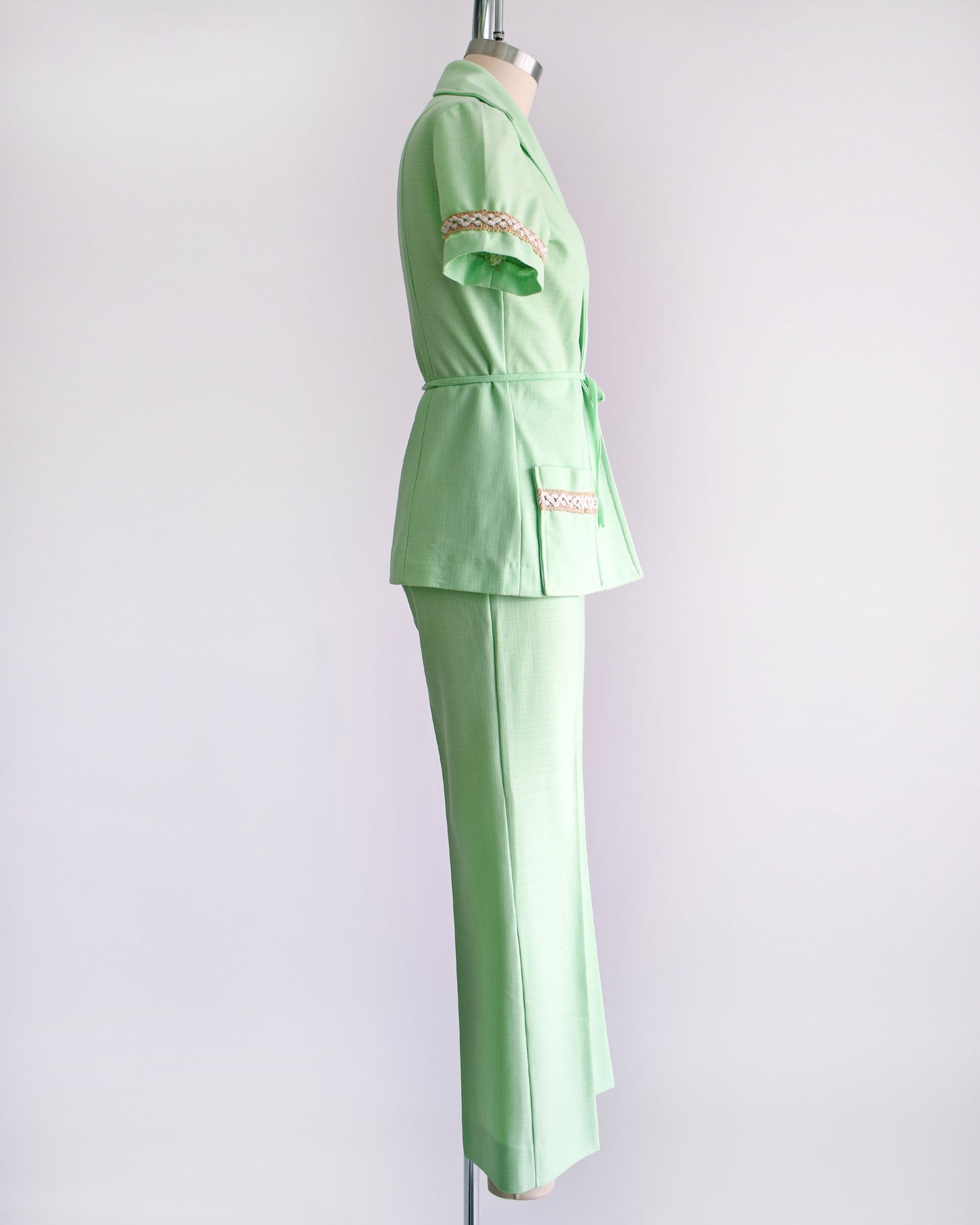 side view of a vintage 1970s mint green pantsuit that has a matching blazer, a tie belt, and wide leg pants