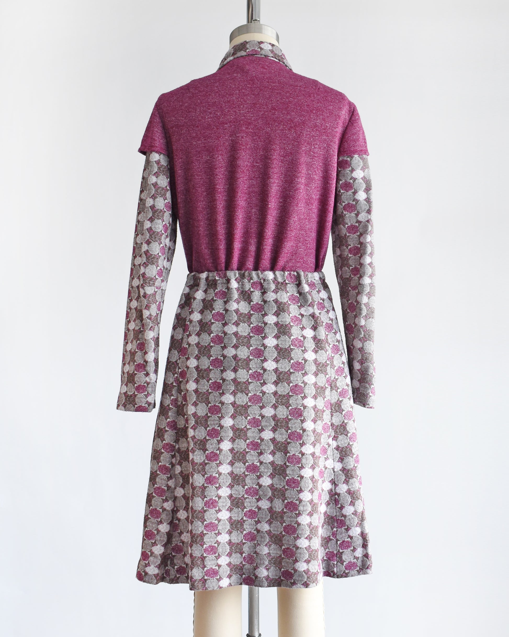 back view of a vintage 1970s dress set that has a purple top and patterned skirt on a mannequin against a white background