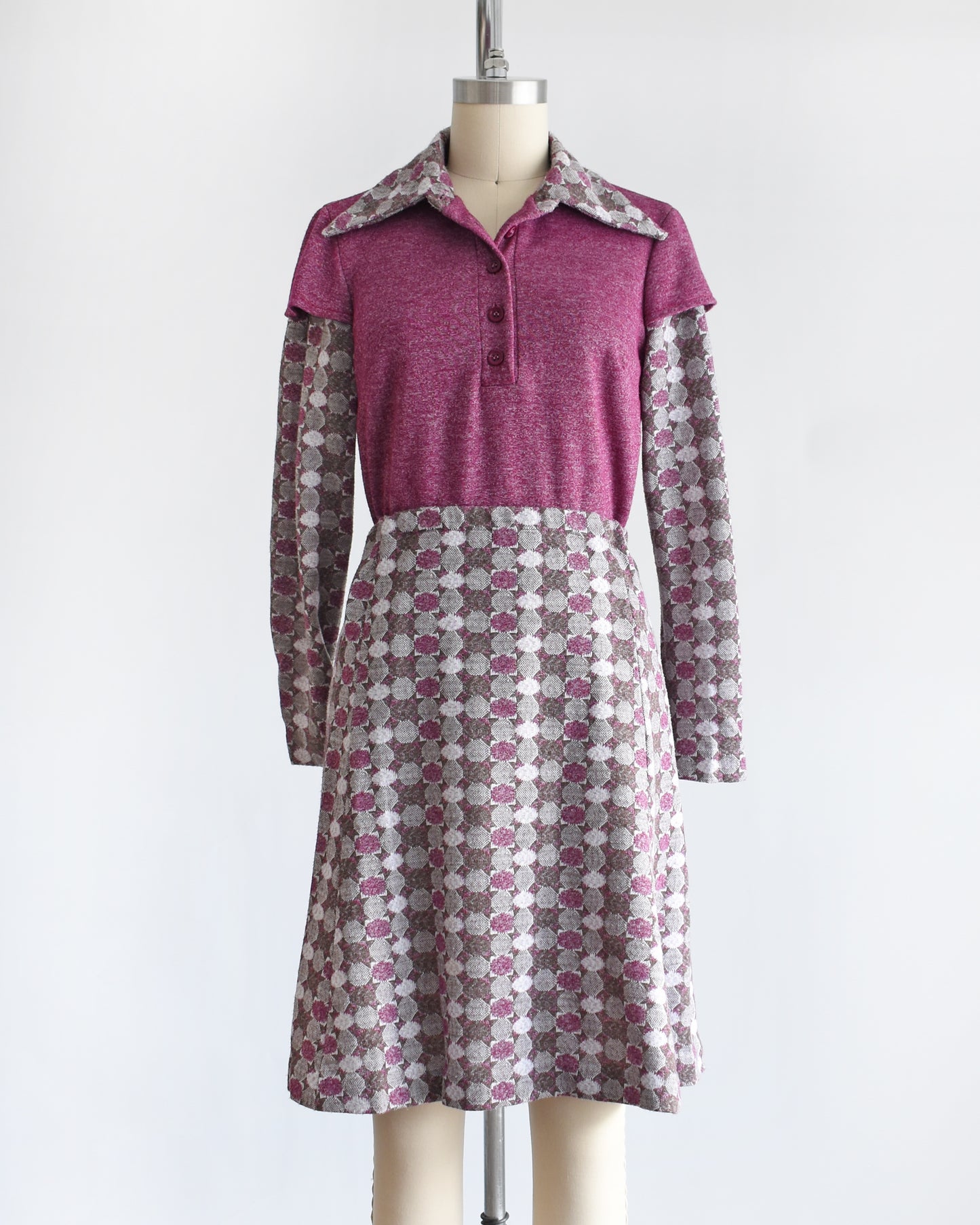 a vintage 1970s dress set that has a purple top and patterned skirt on a mannequin against a white background. the top has a few buttons unbuttoned at the collar.