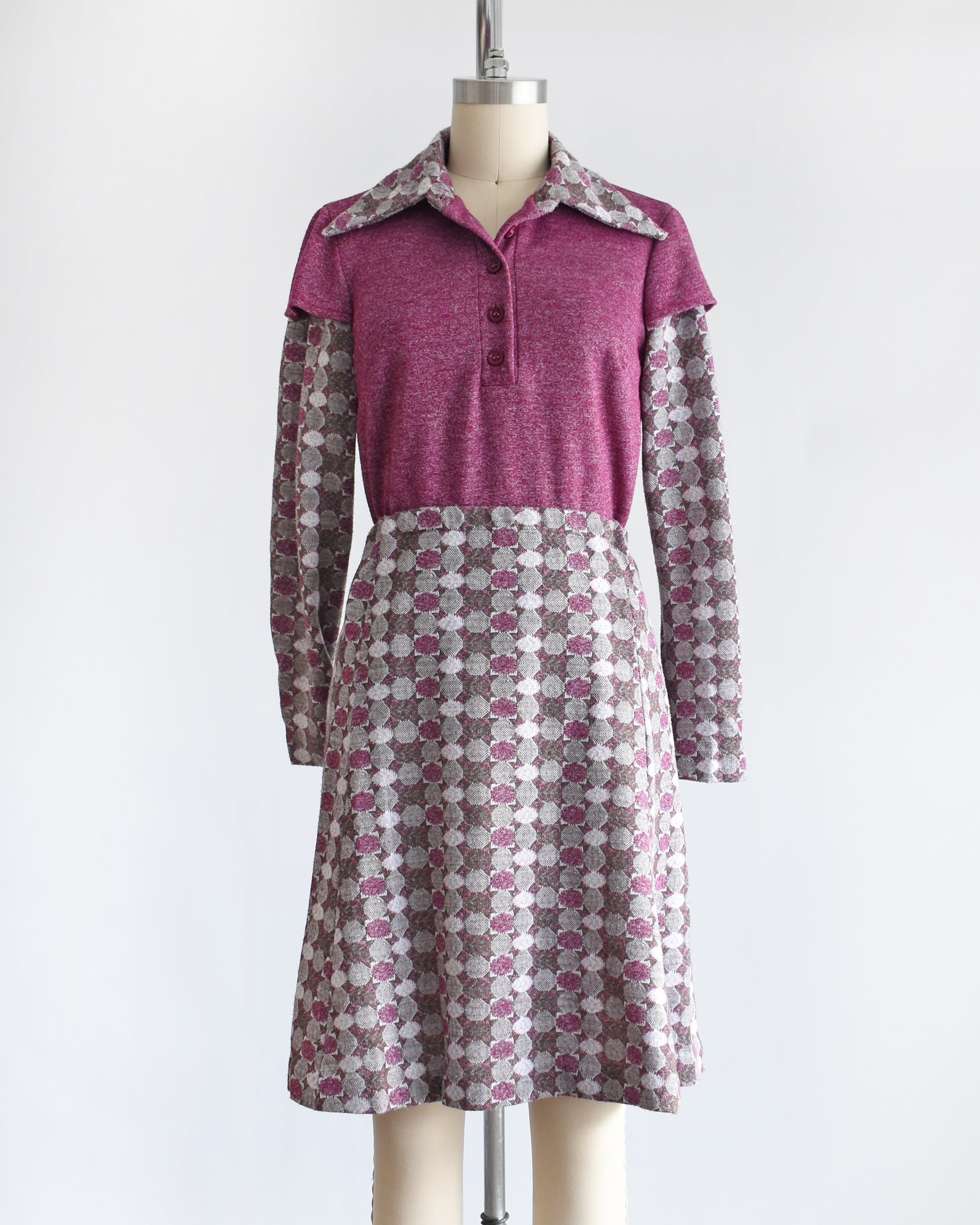 a vintage 1970s dress set that has a purple top and patterned skirt on a mannequin against a white background. the top has a few buttons unbuttoned at the collar.