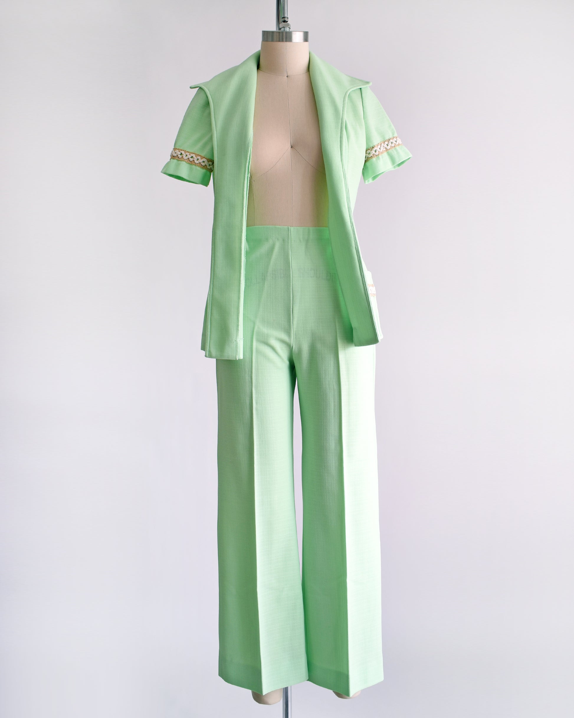 a vintage 1970s mint green pantsuit that has a matching blazer, a tie belt, and wide leg pants. the blazer is open and the belt is removed in this photo