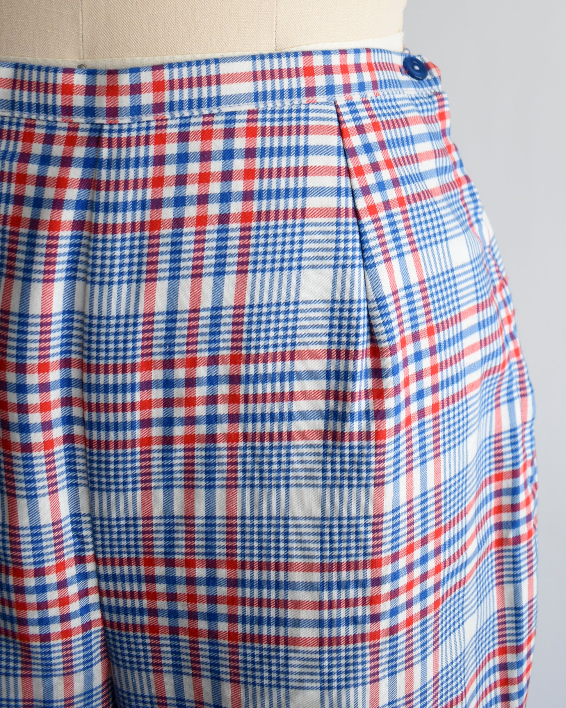 close up of the waist and hip area of the pants showing the side button and plaid print