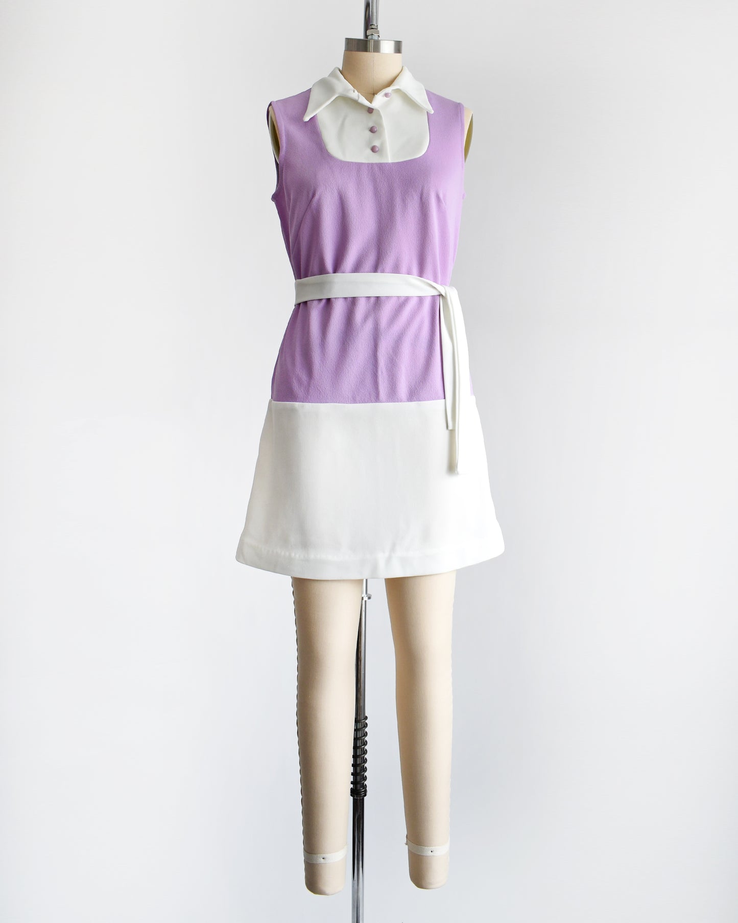 a vintage 1960s purple and white mod mini dress with a white belt around the waist