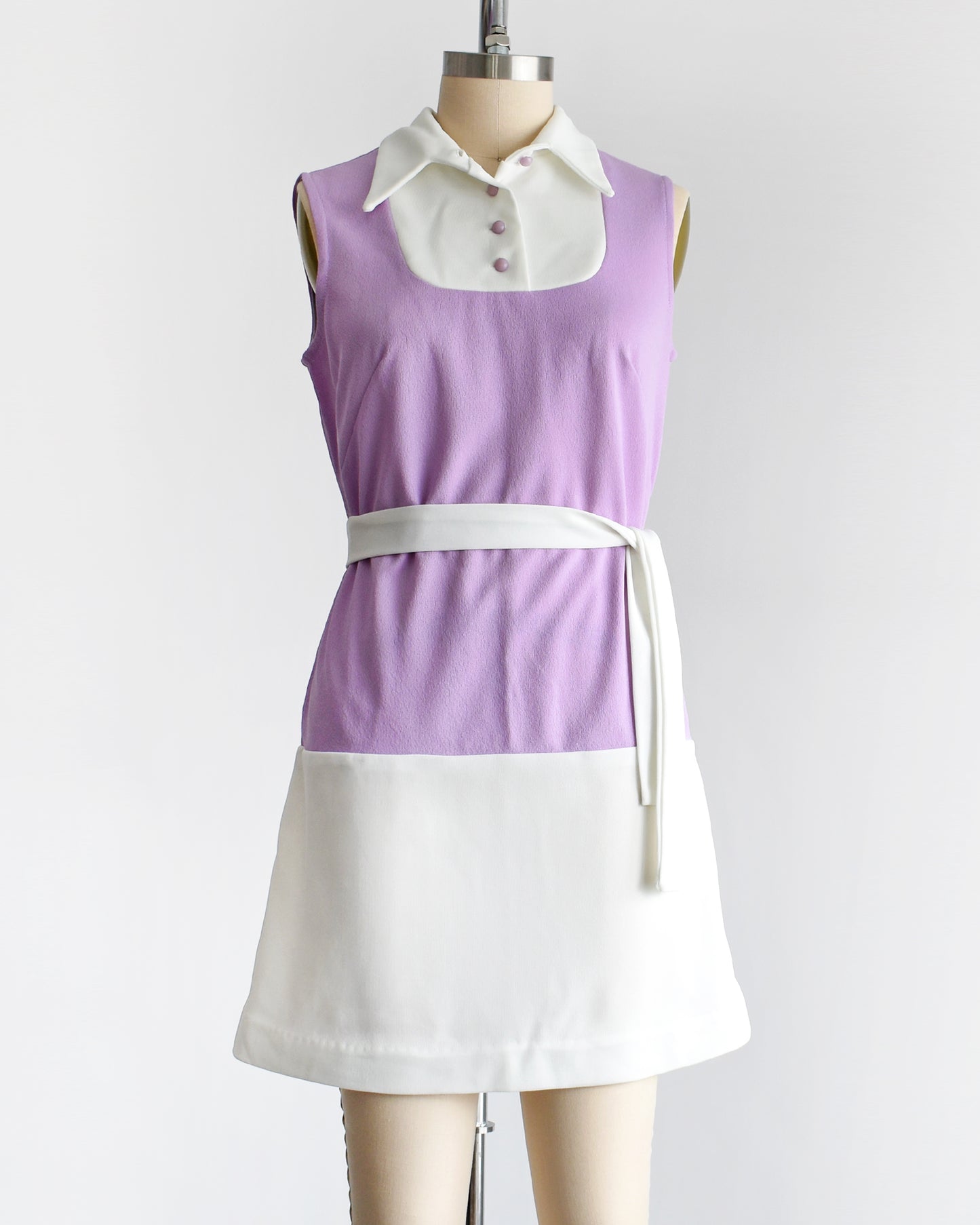 a vintage 1960s purple and white mod mini dress with a white belt around the waist