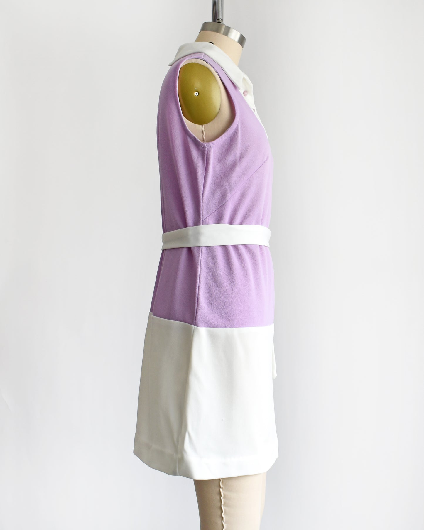 side view of a vintage 1960s purple and white mod mini dress with a white belt around the waist