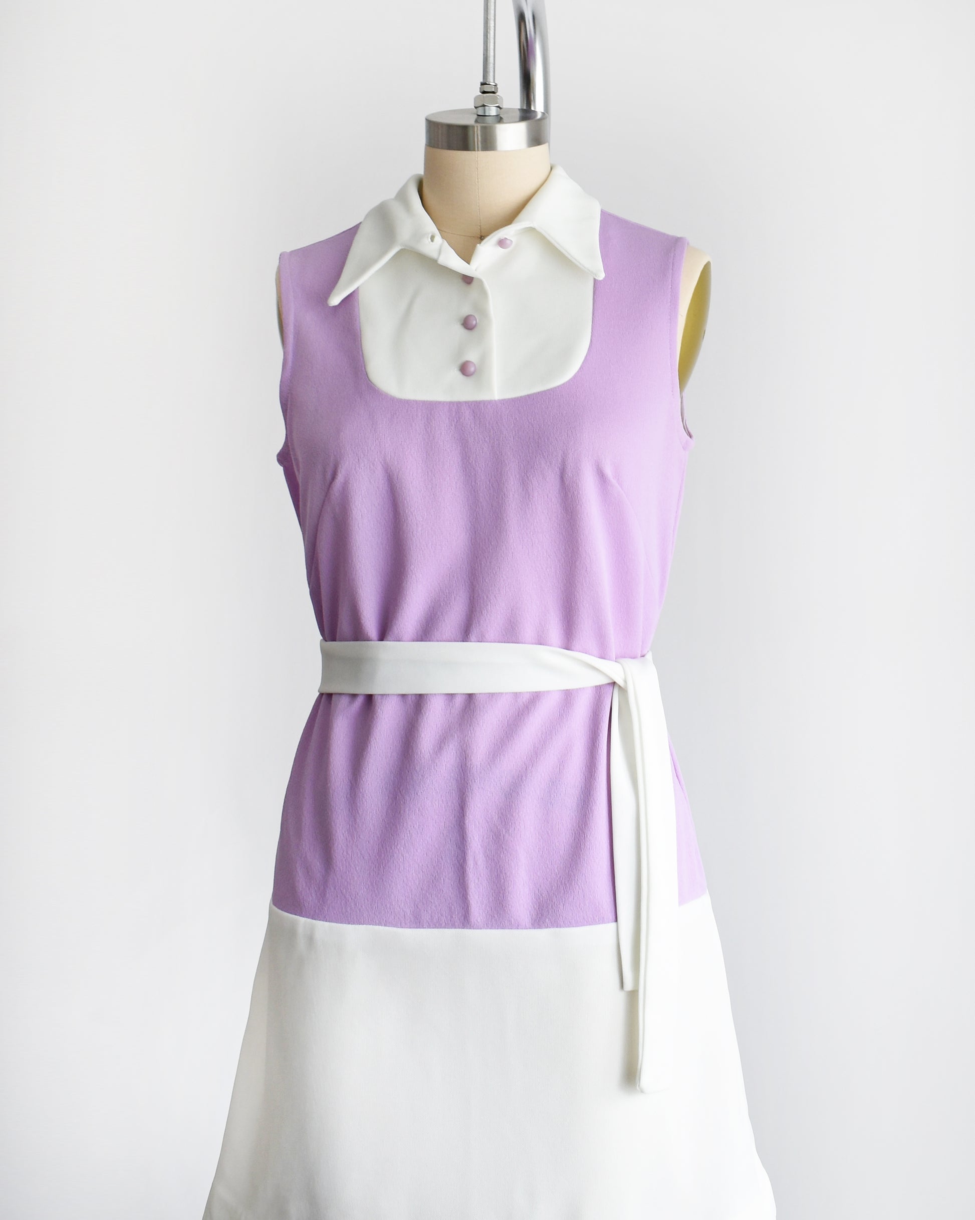 side front view of a vintage 1960s purple and white mod mini dress with a white belt around the waist