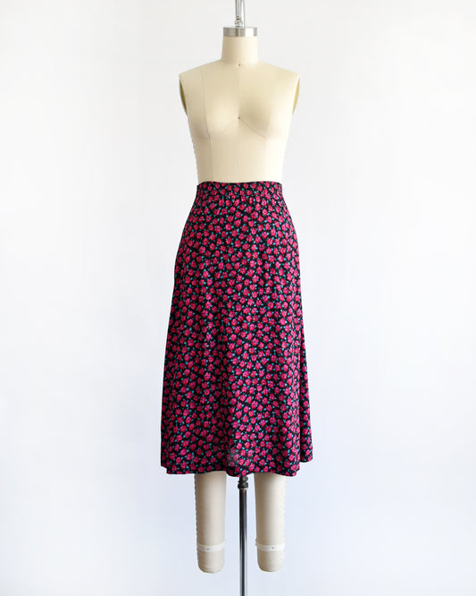 A vintage 1990s high-waisted A-line skirt with a dense pink and dark red floral print, displayed on a cream-colored dress form mannequin against a plain white background.