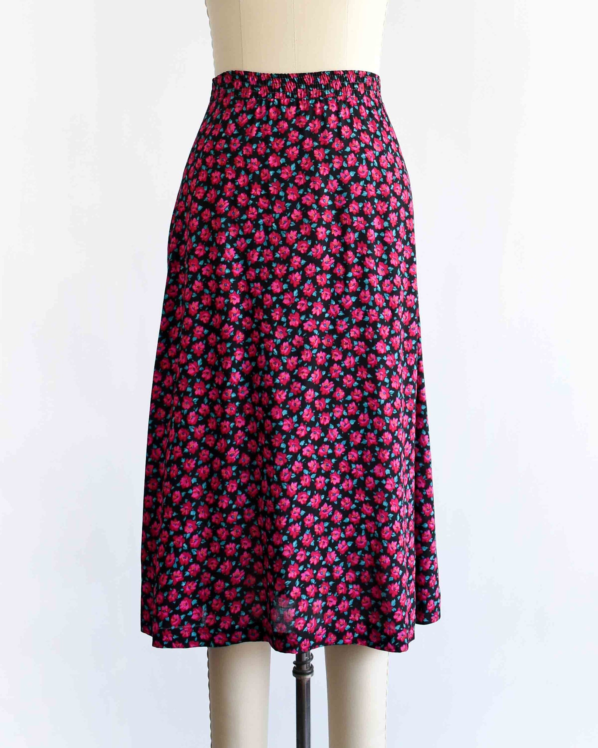 A vintage 1990s high-waisted A-line skirt with a dense pink and dark red floral print, displayed on a cream-colored dress form mannequin against a plain white background.